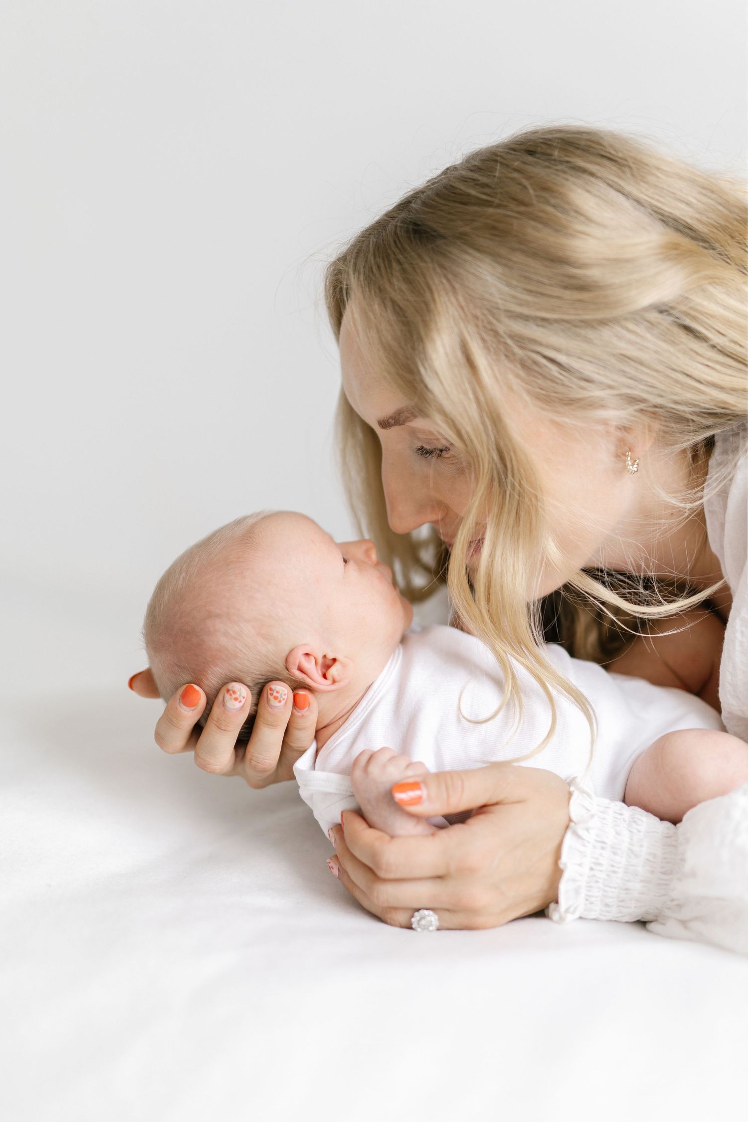 Intimate portrait of parent gently kissing newborn baby against white background.