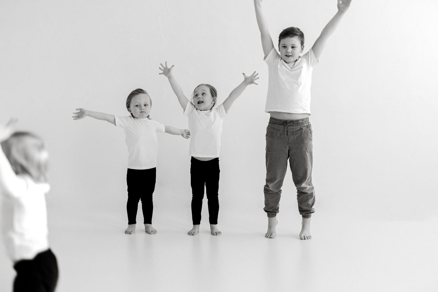 A series of black and white photos showing joyful children jumping and playing against a white background.