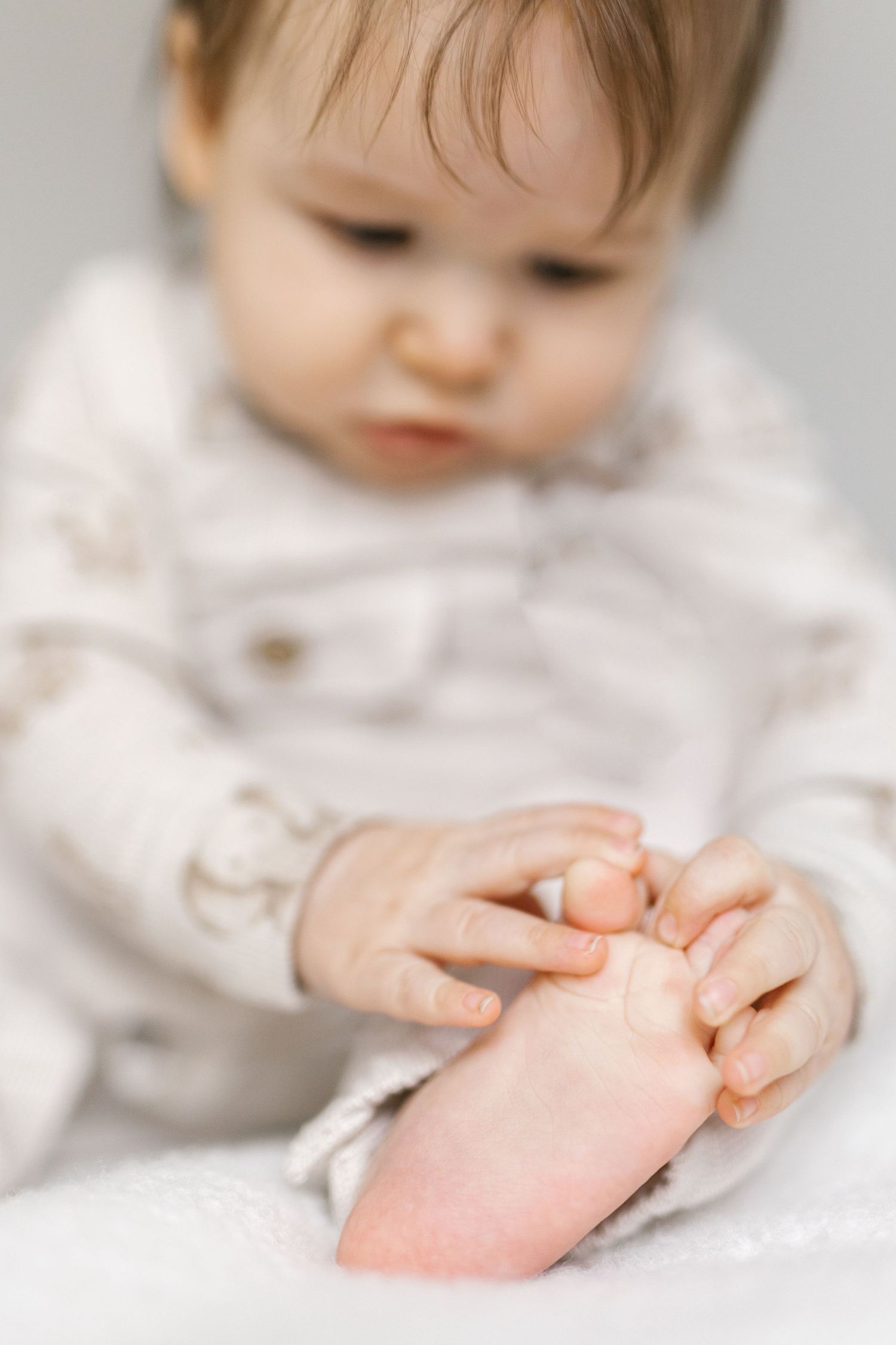 Close-up sequence of small hands touching tiny feet on white background.