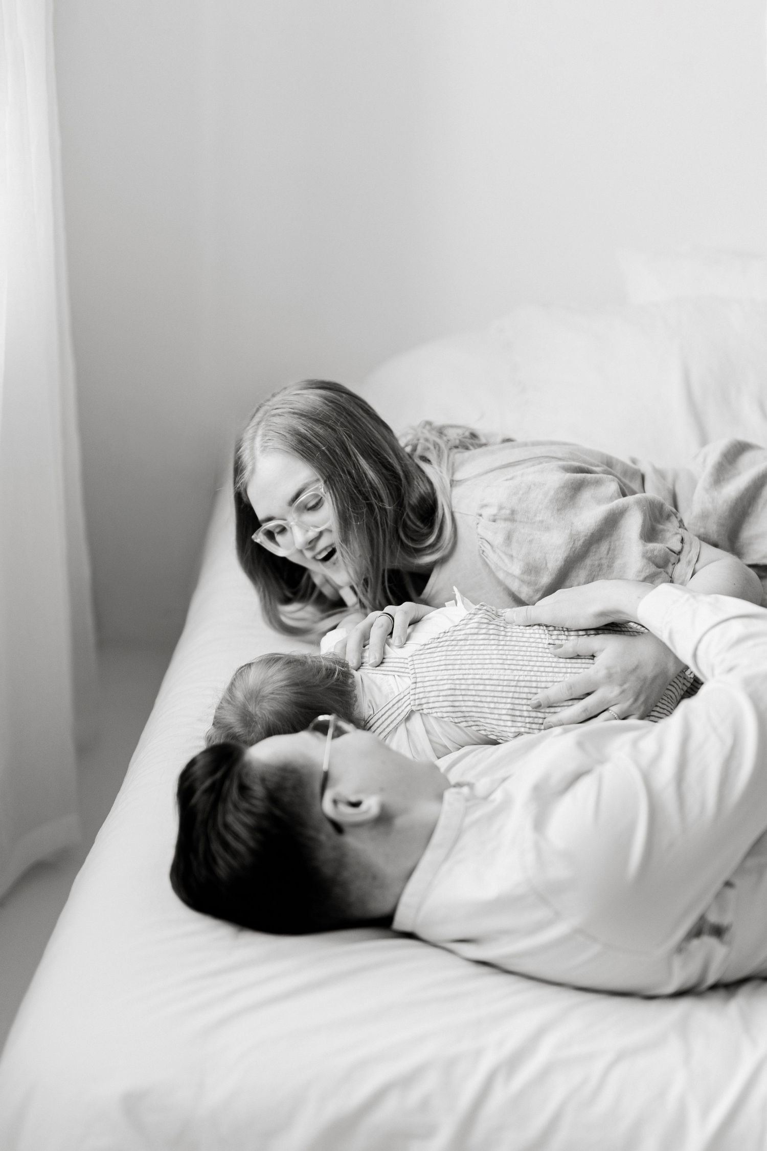 Black and white photo of couple lying together on bed.