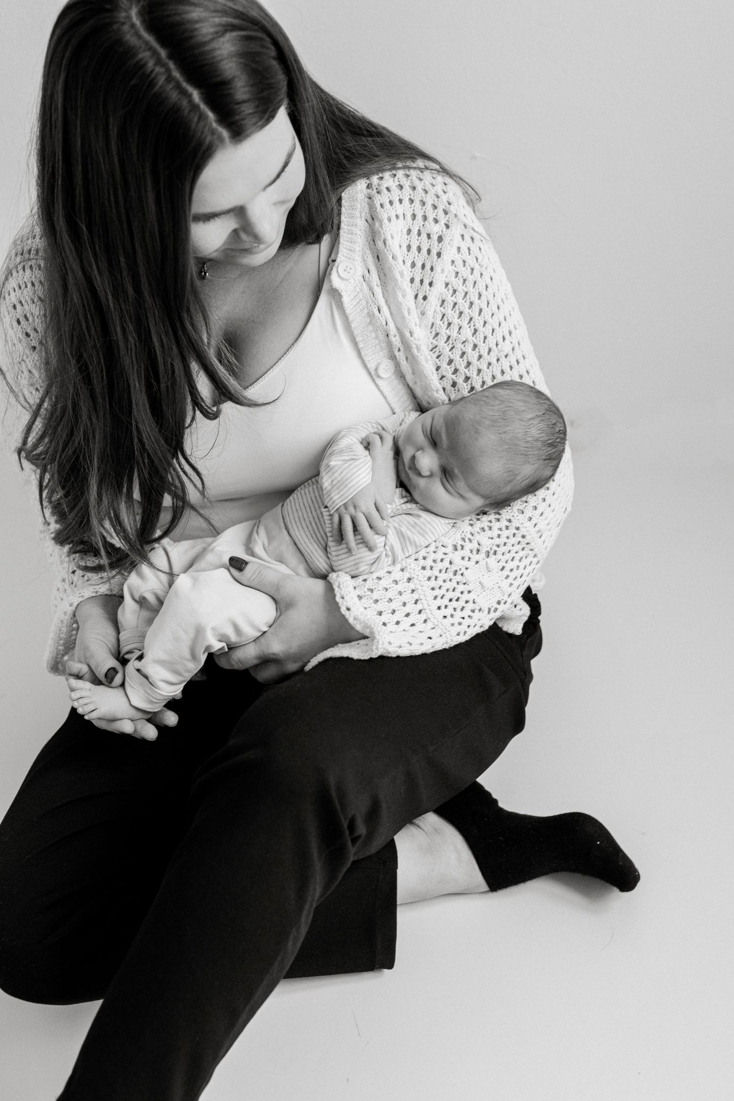 Black and white portrait of mother in lace top holding sleeping newborn.
