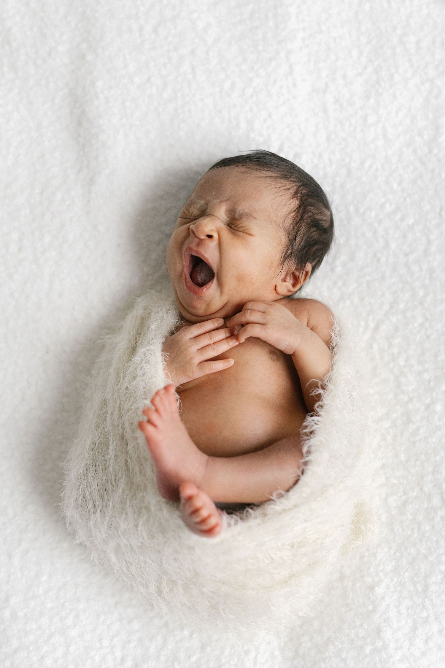 Newborn baby posed on fluffy white backdrop in various natural sleeping positions.