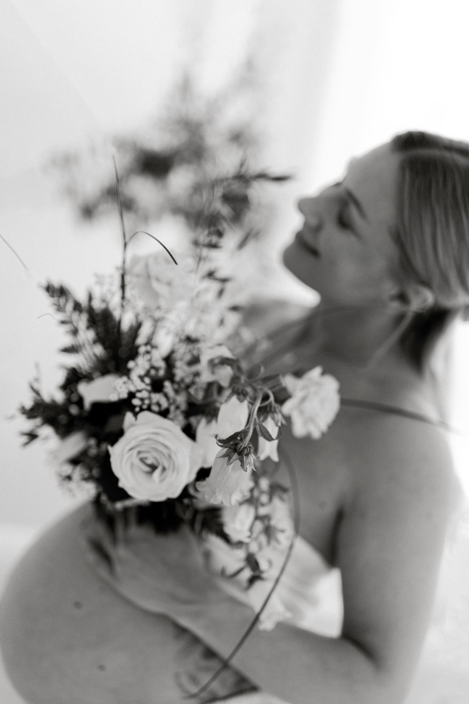 Black and white artistic shot of pregnant woman admiring floral arrangement.