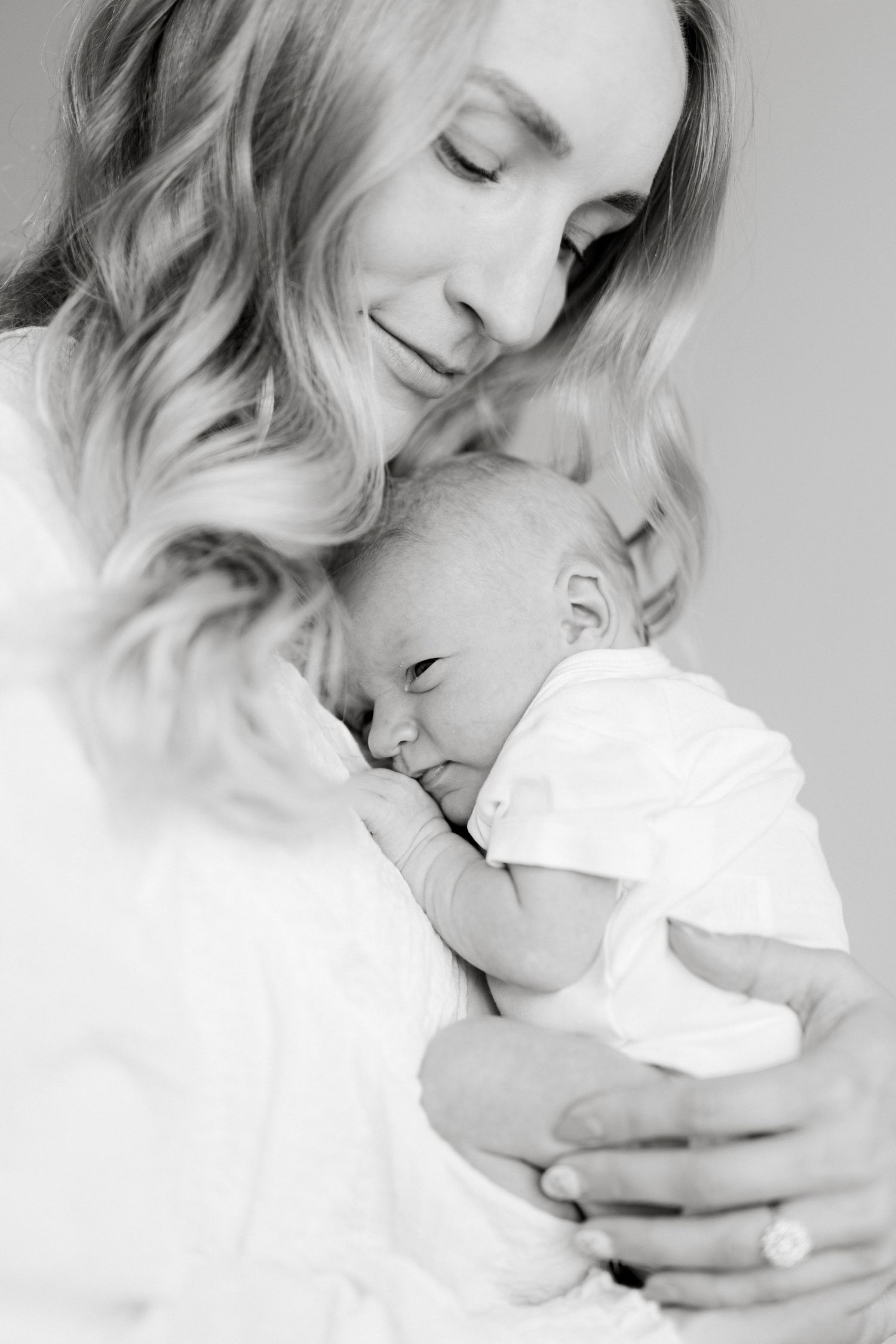 A tender moment captured in black and white as a parent cuddles with their newborn baby.