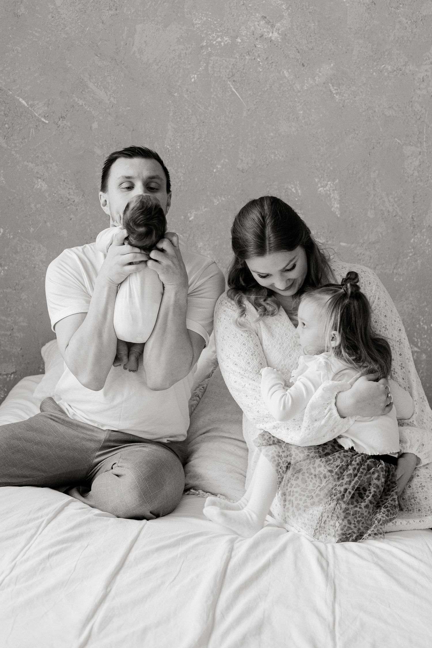 Black and white series of family cuddling together on bed.