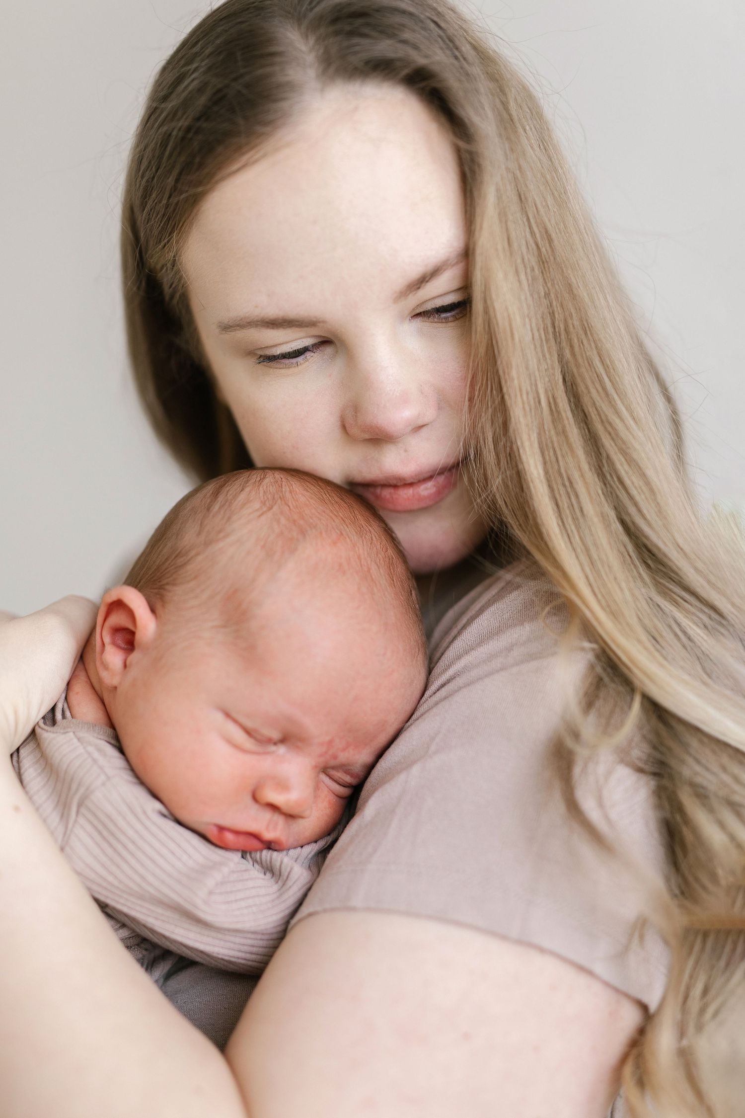 Gentle portrait series of parent cuddling with sleeping newborn.