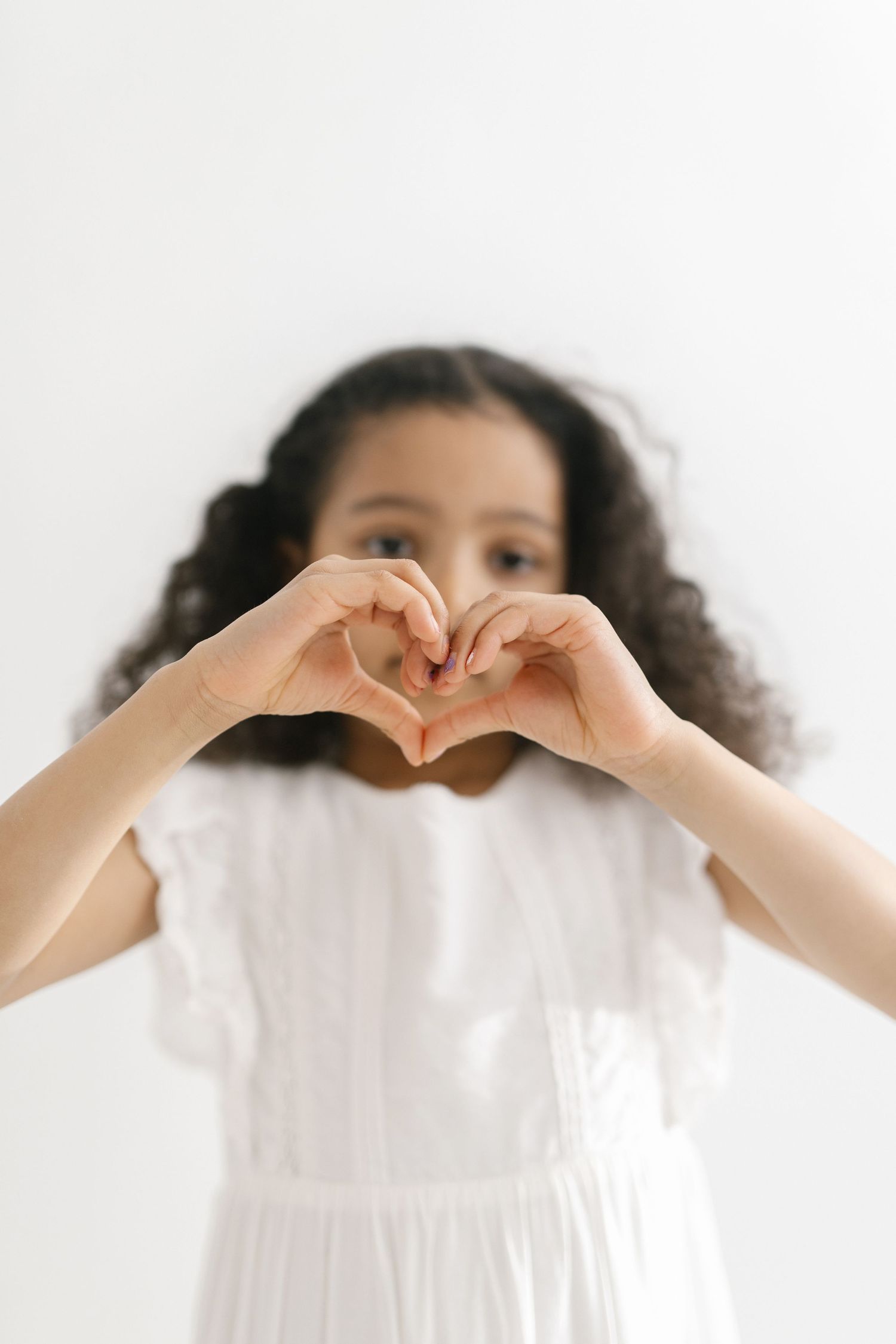 Hands forming heart shape against white background in sequential photos.