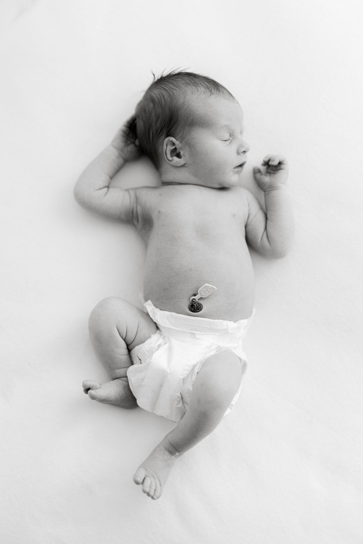 Artistic black and white photos of newborn baby lying on white background.