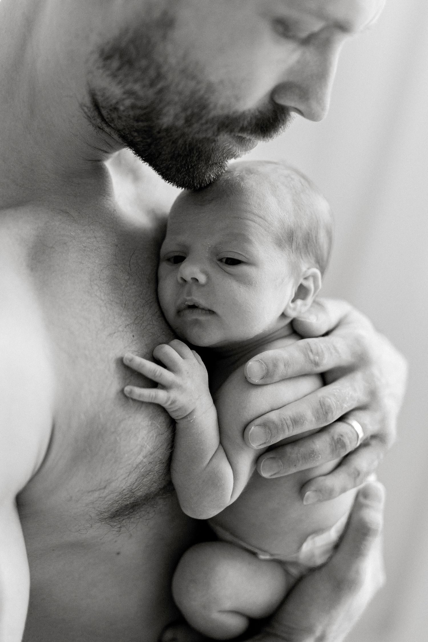 Close-up black and white photos capturing gentle moments between parent and infant.