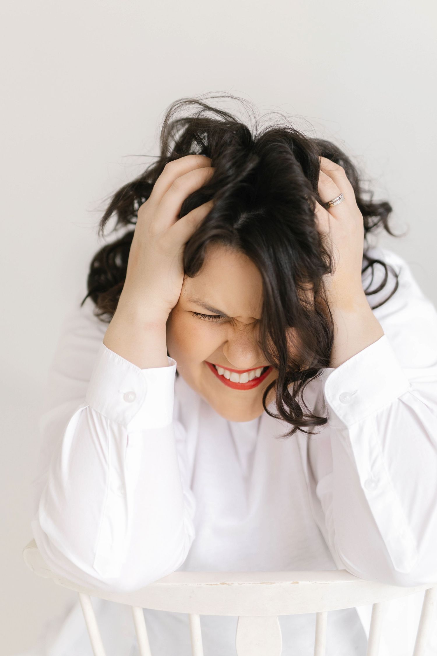 Candid shots of someone in white clothing running hands through dark hair with bright smile.