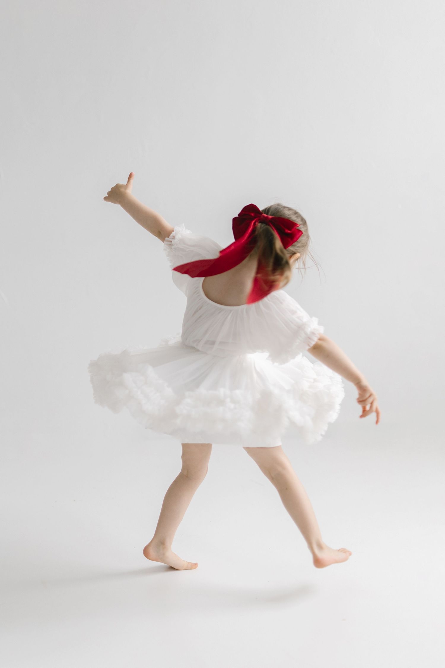 Dynamic dance poses showing movement in a white dress with red bow.