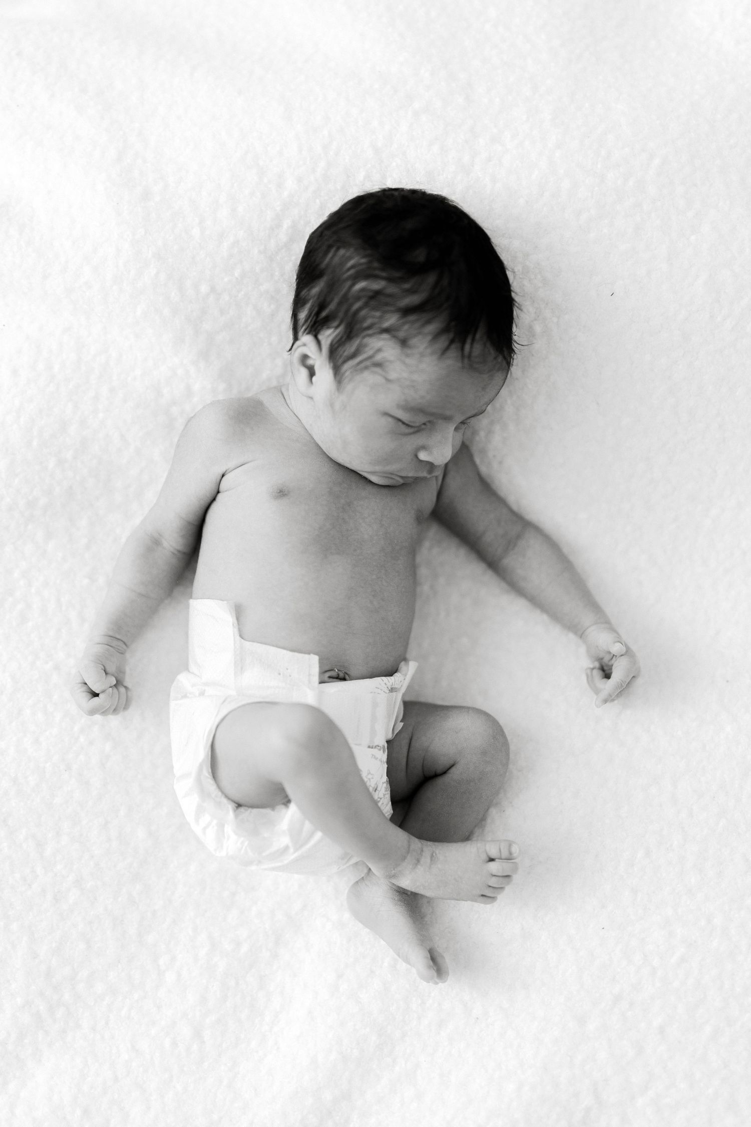 Minimalist black and white series showing newborn baby resting on white background.