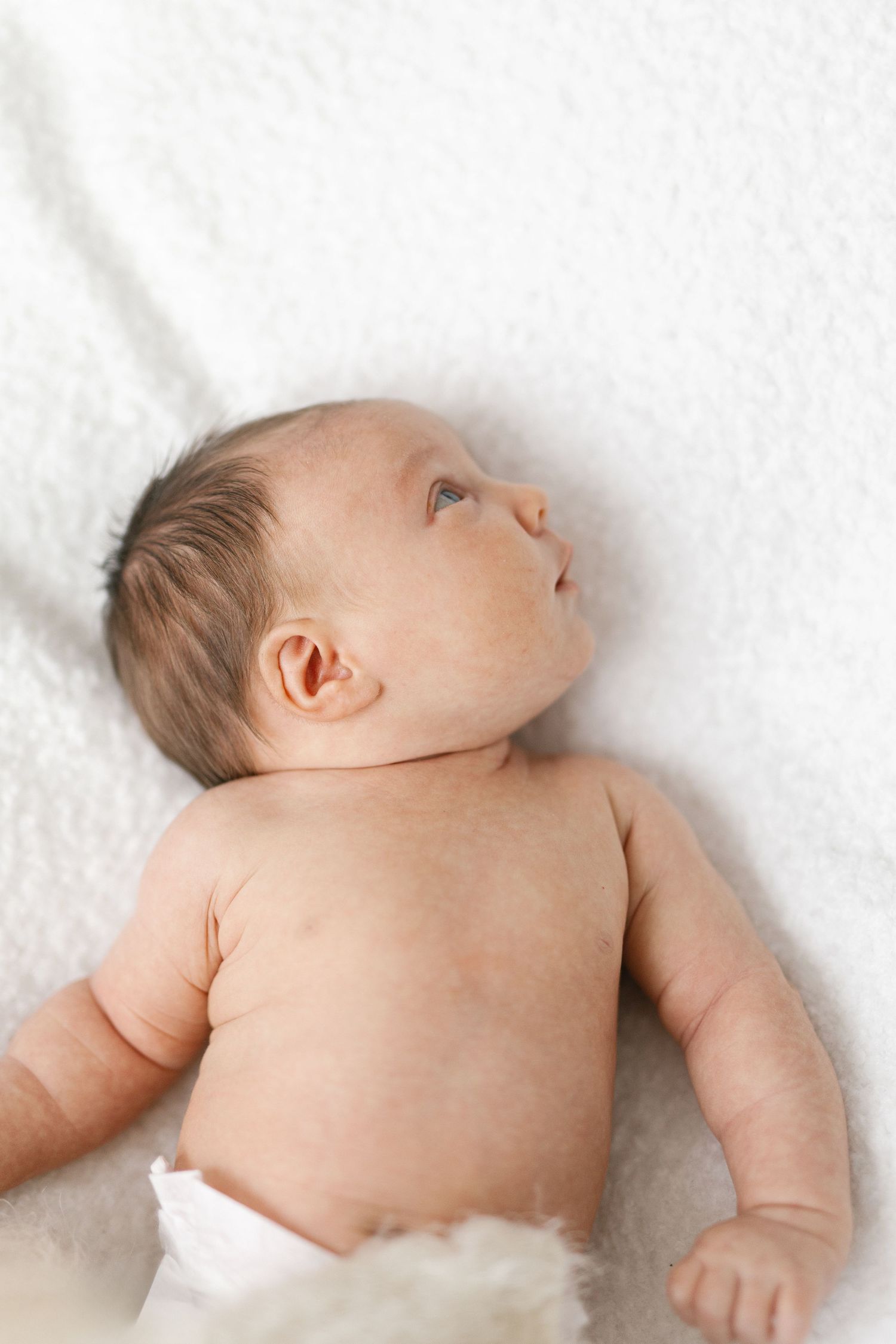 Newborn baby lying on soft white blanket in various resting positions.