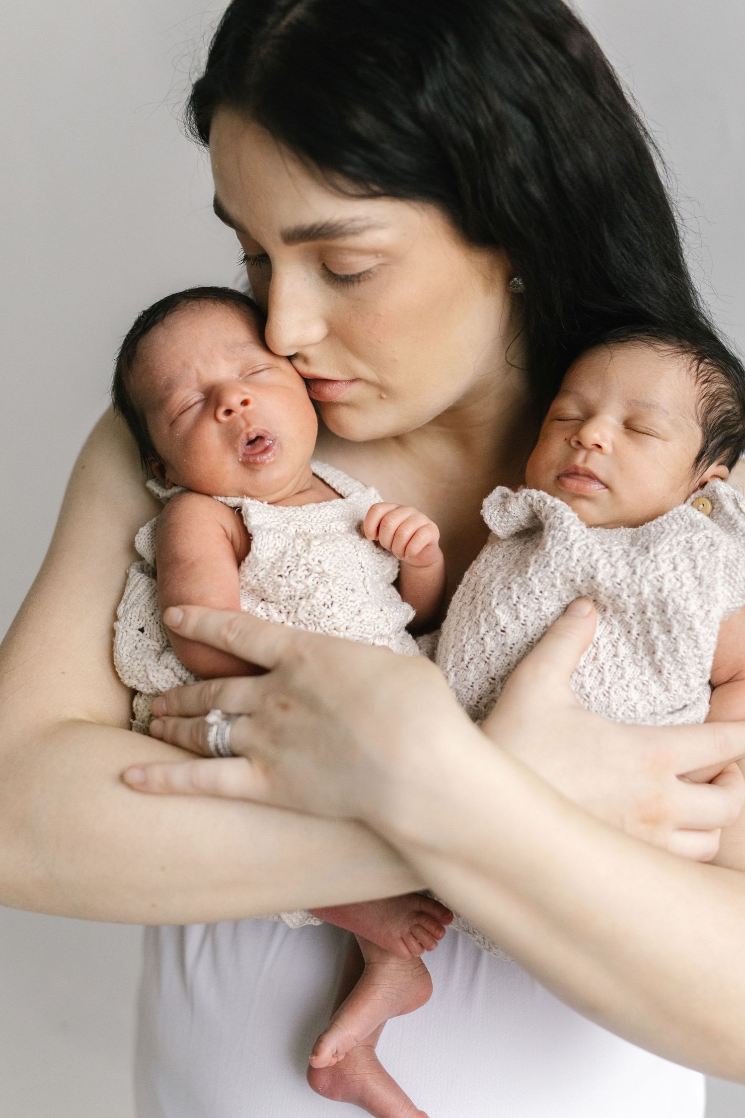 A tender sequence of a parent cradling and kissing a newborn baby wearing white lace.