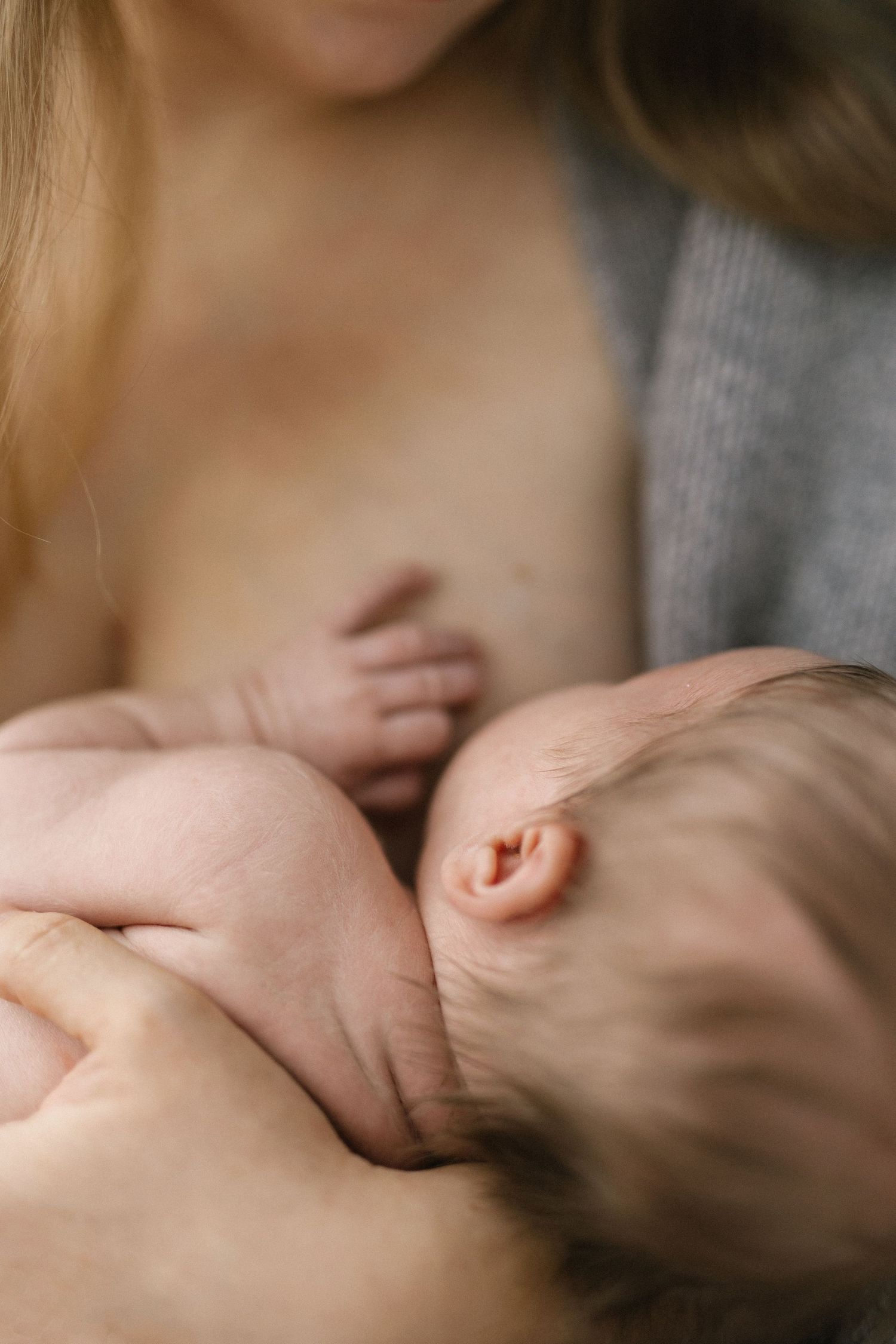 Gentle moment of parent cradling sleeping newborn in soft lighting.