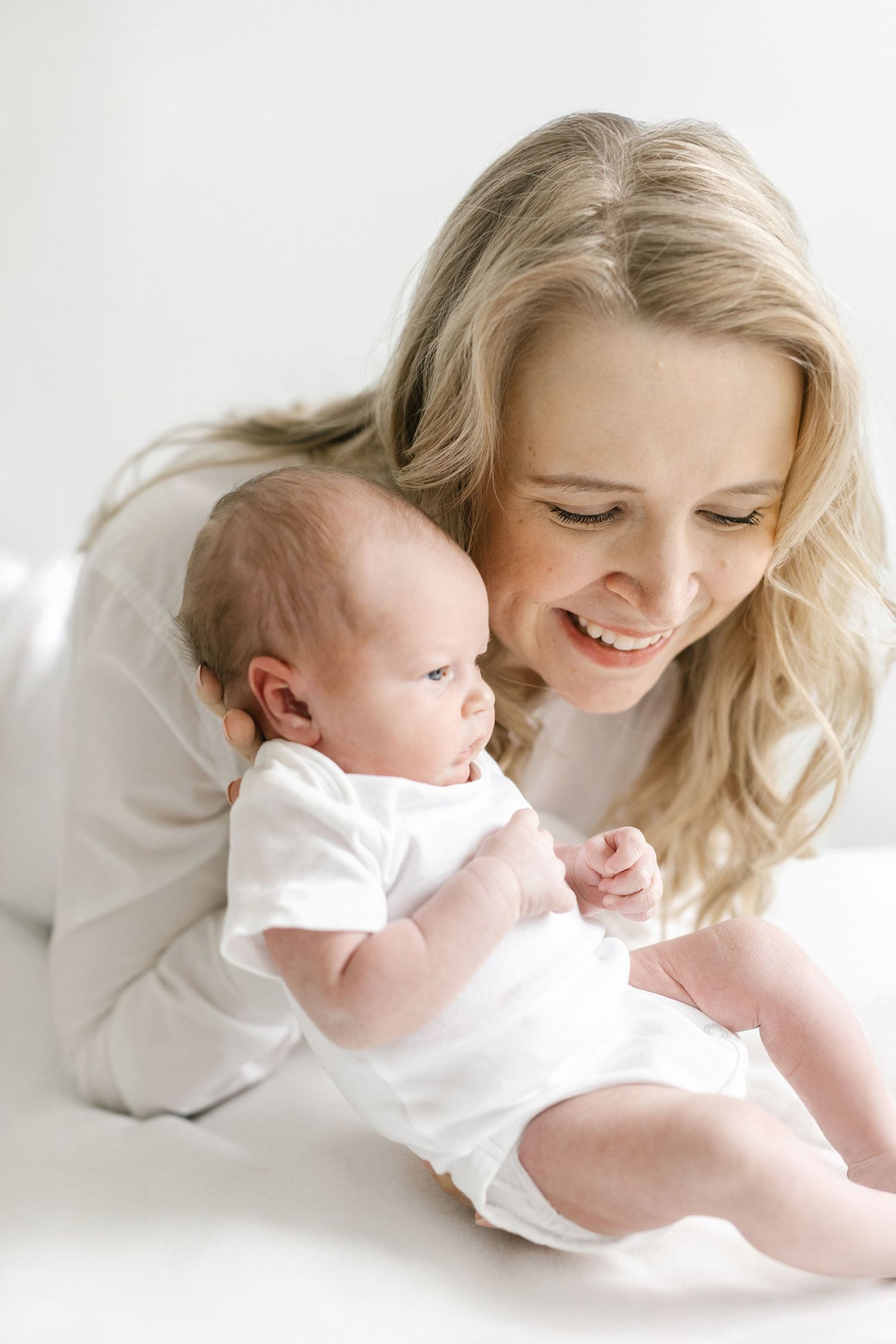Intimate portraits of mother and baby dressed in white sharing tender moments together.