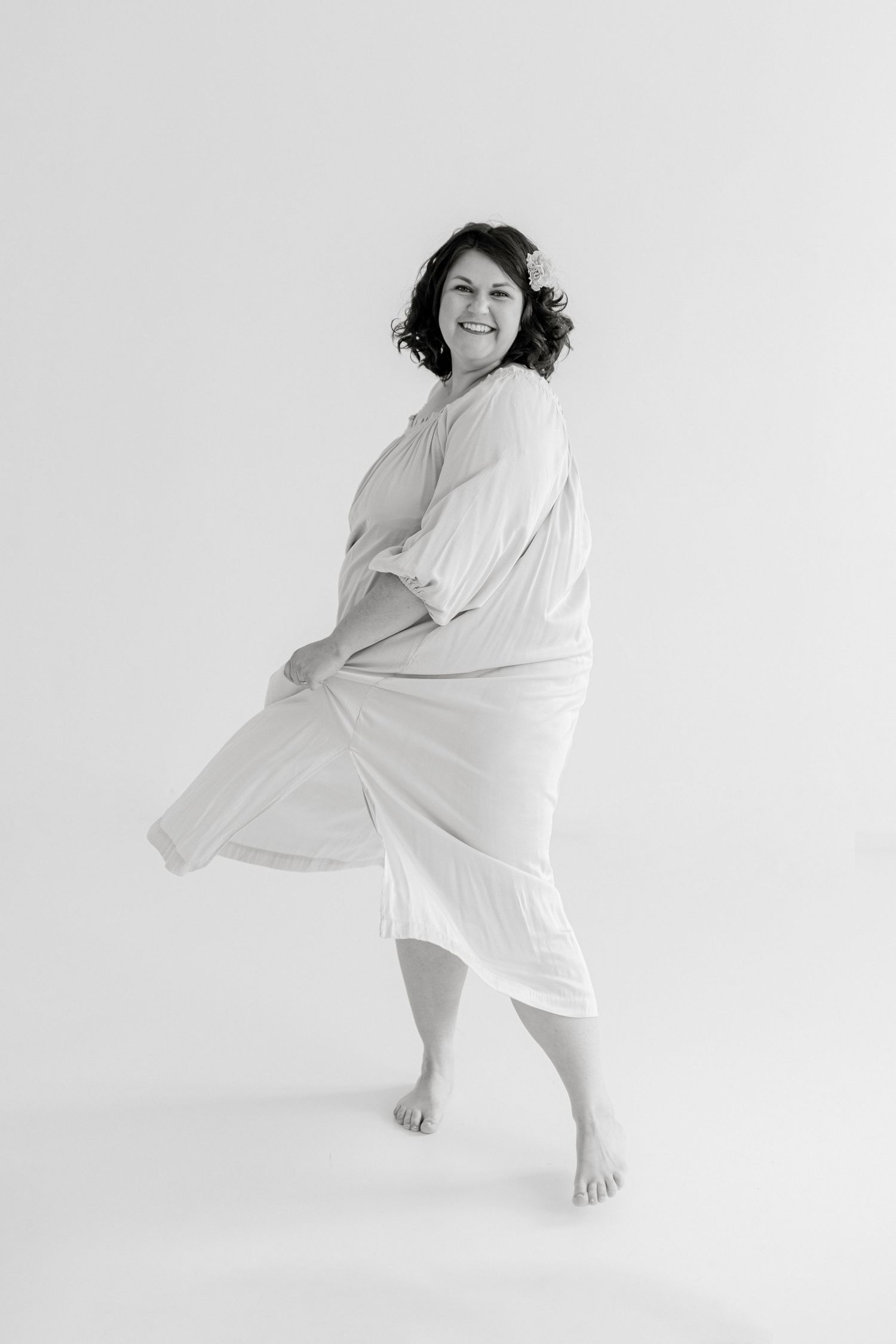 Figure in flowing white fabric dancing against minimalist background.