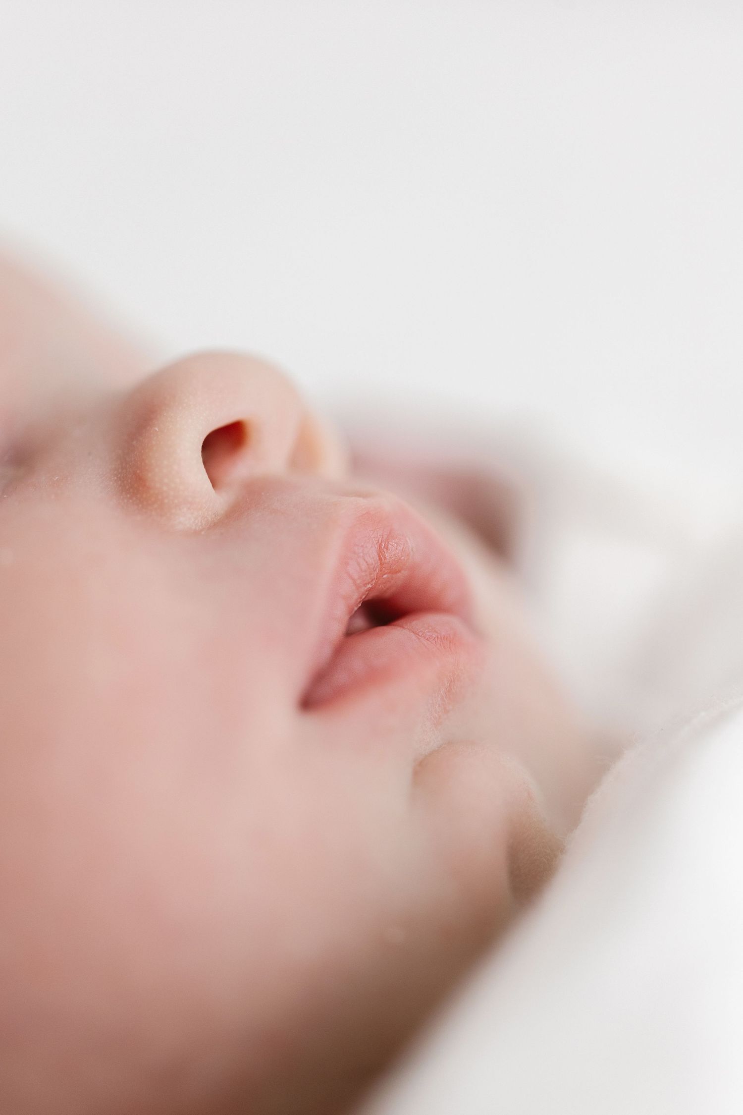 Extreme close-up of a sleeping newborn's nose and mouth in soft focus.