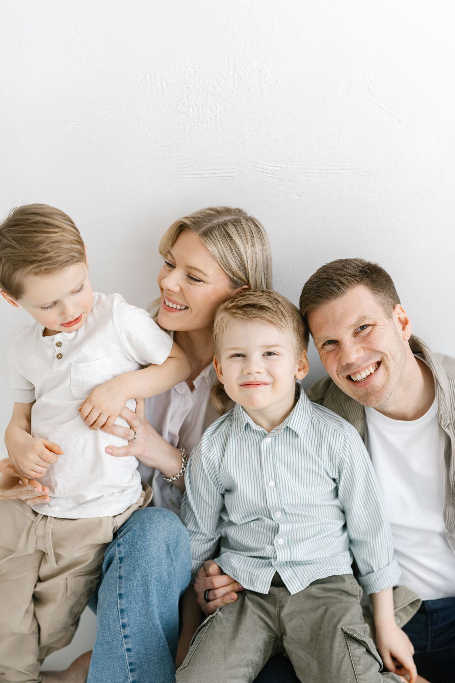 A joyful family portrait series showing playful candid moments together on a light background.