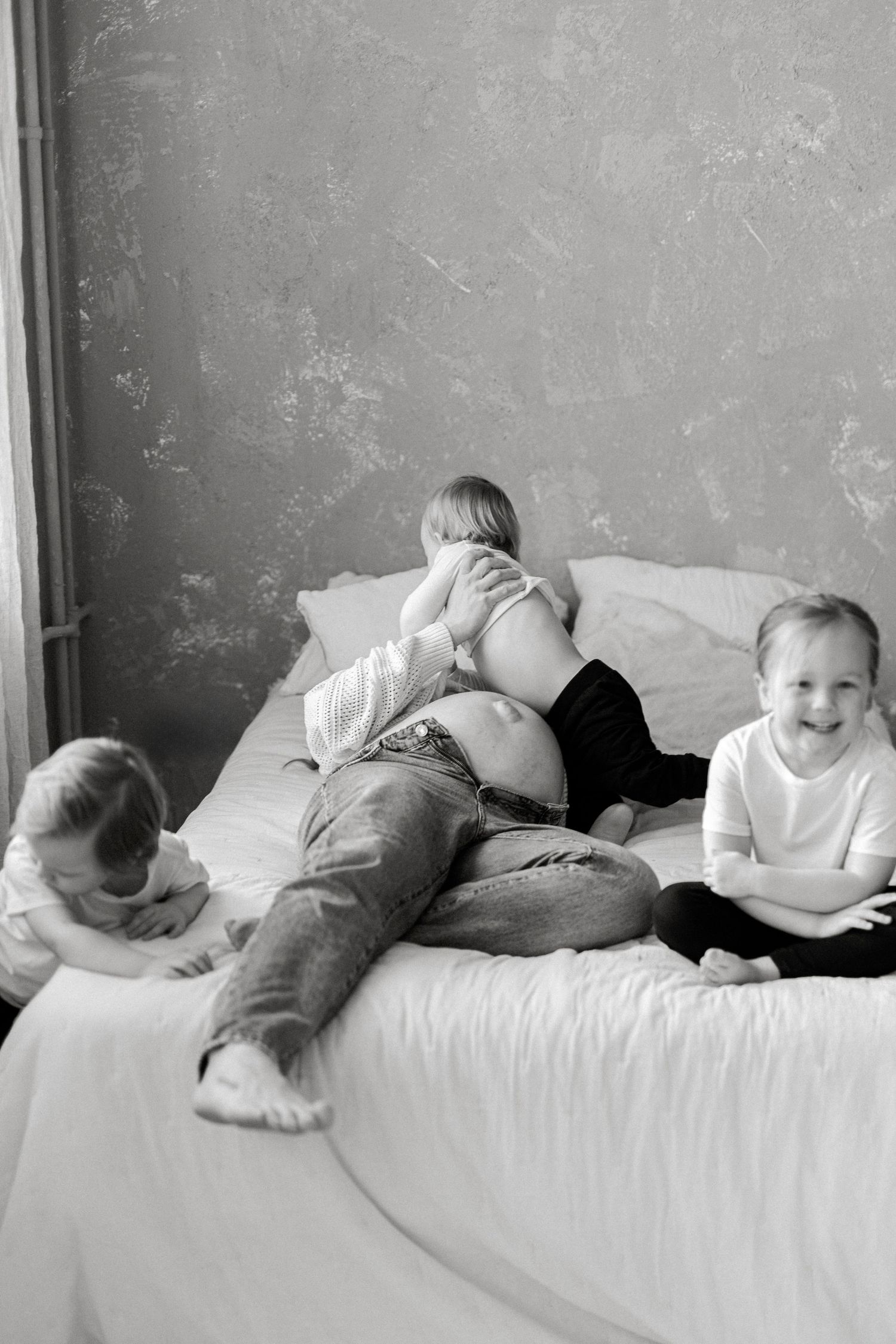 A series of black and white photos showing a sleeping baby in different positions on a white bed.