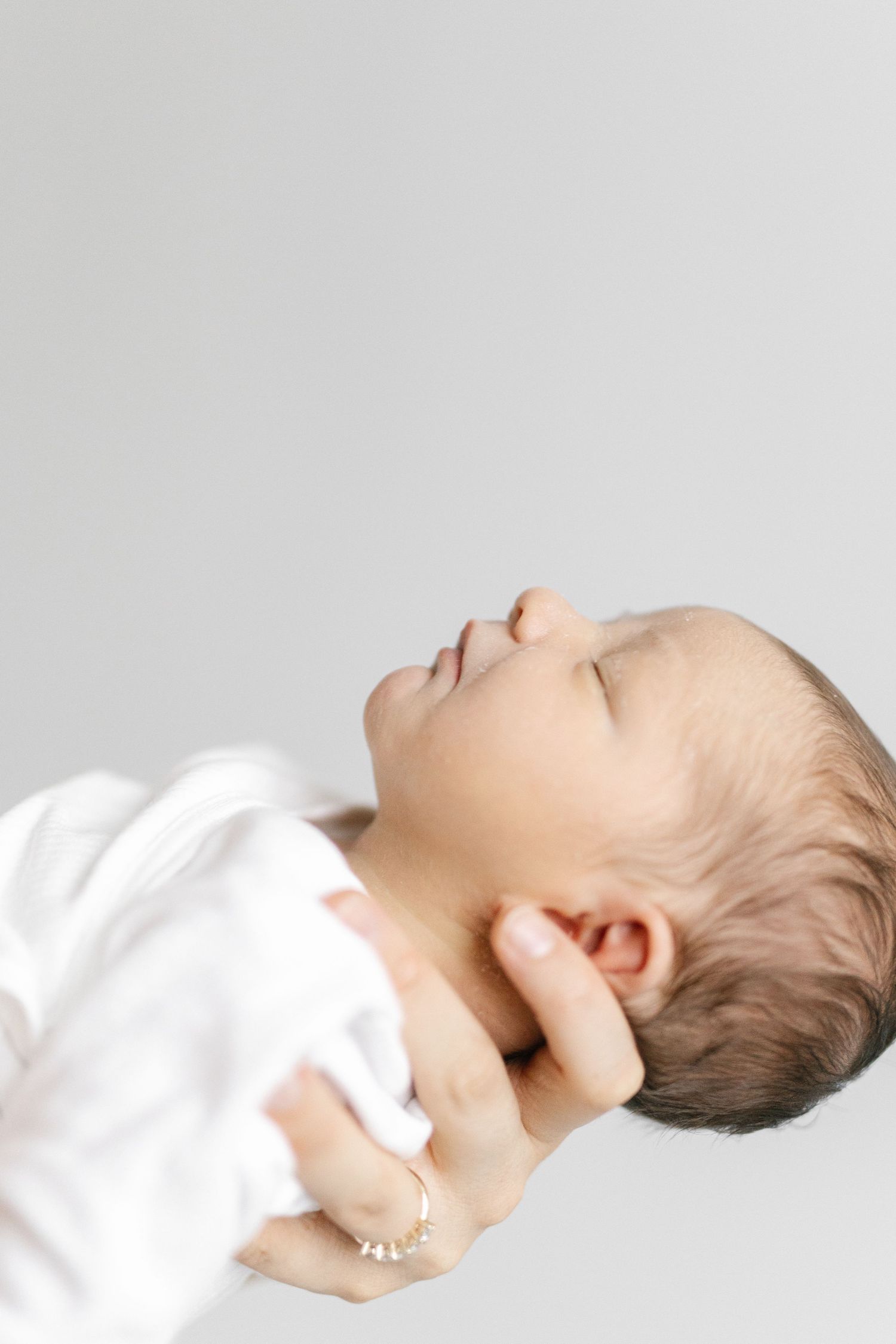 Sleeping baby in white clothing lying on back against white background in sequence of peaceful poses.