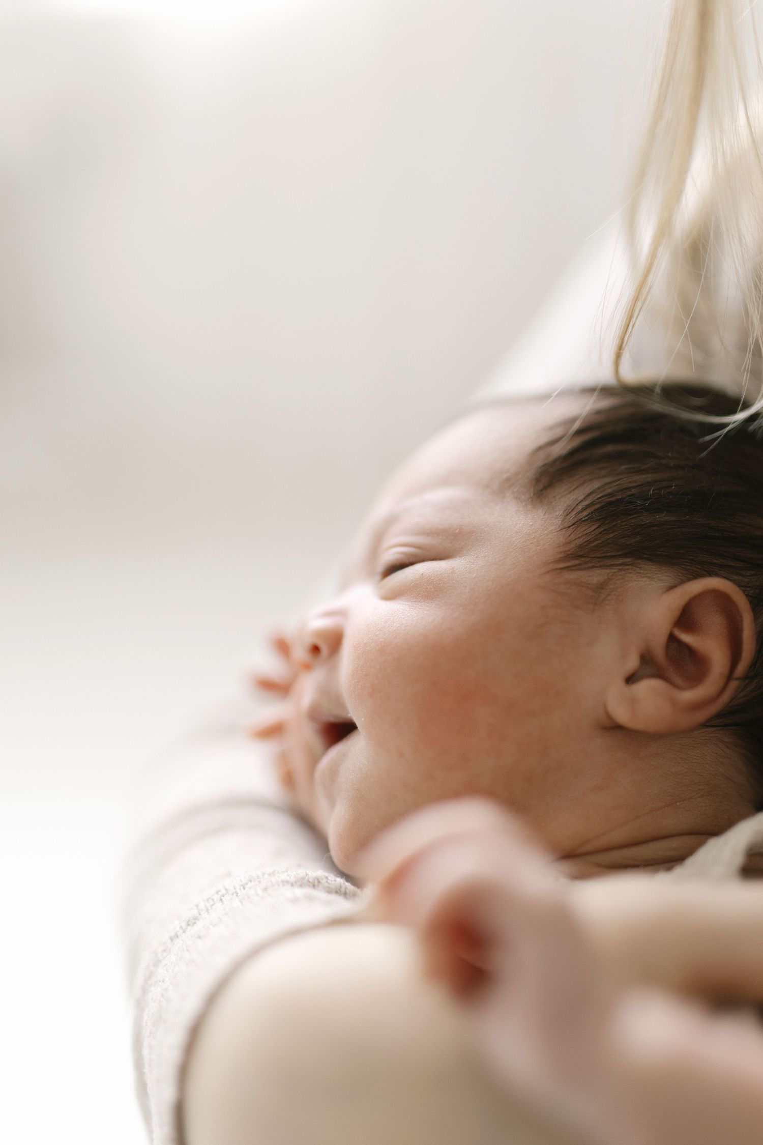 Soft focus profile shot of a sleeping newborn in natural light.