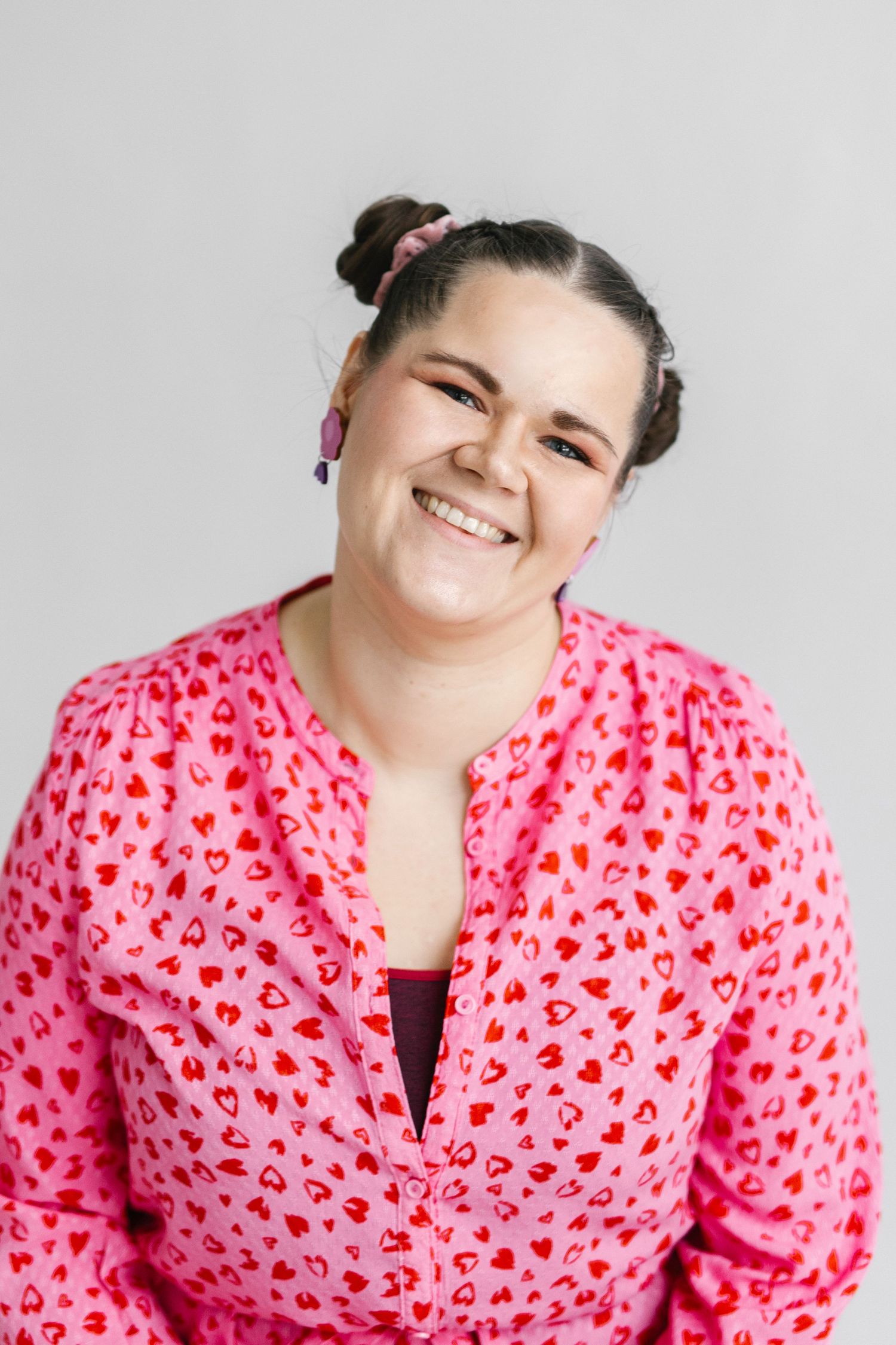 Person in pink heart-patterned dress showing playful expressions.