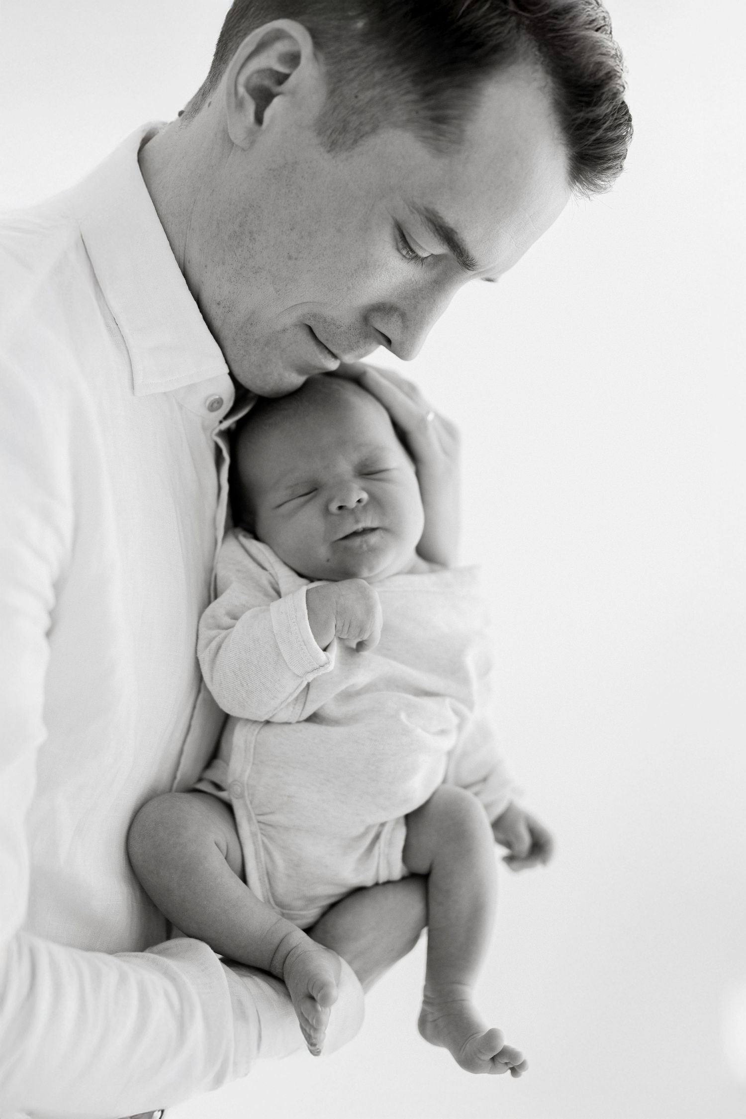 Black and white series of parent cradling sleeping newborn against white background.