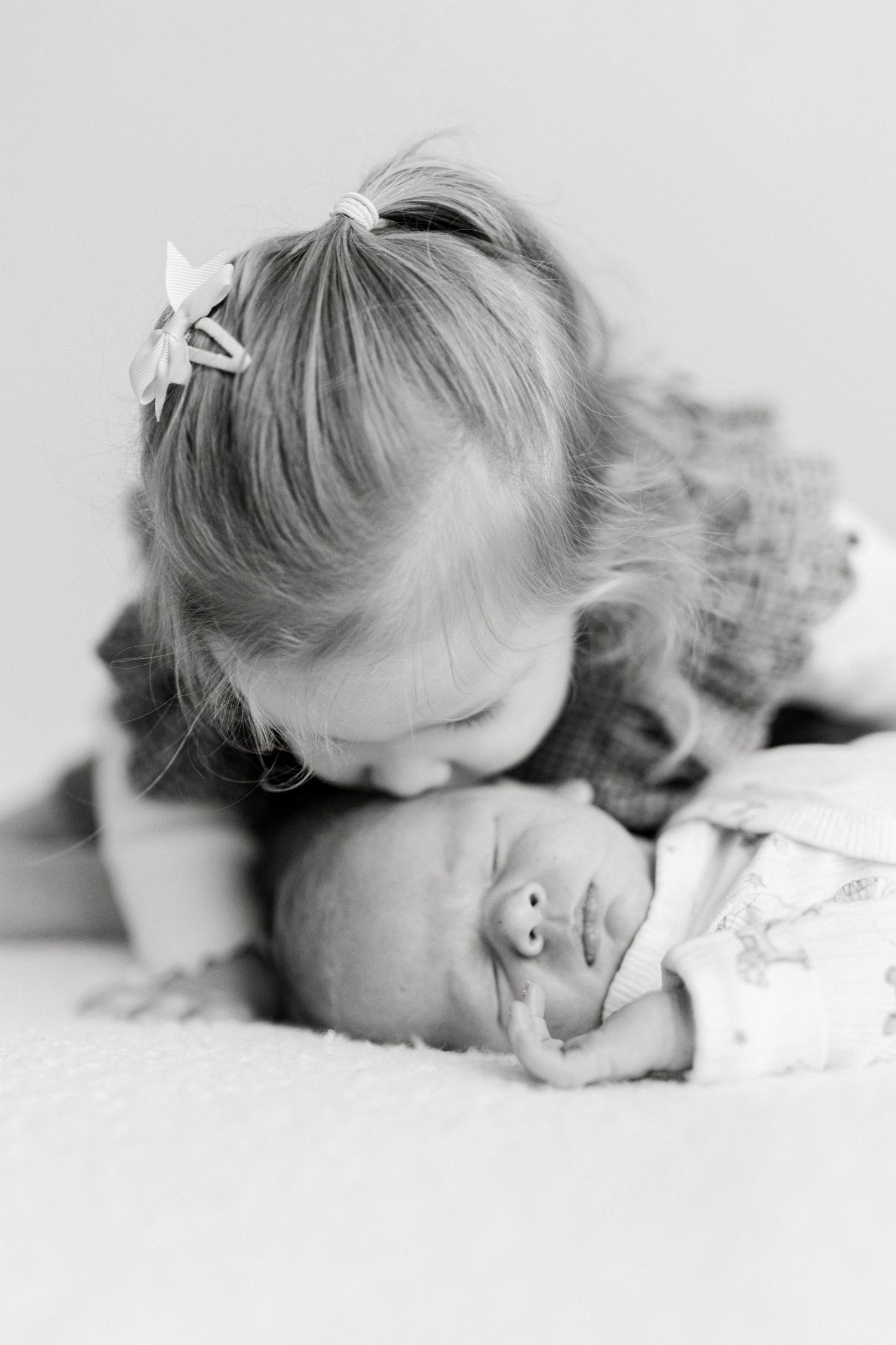 Young child sleeping peacefully on white bedding in black and white portrait sequence.