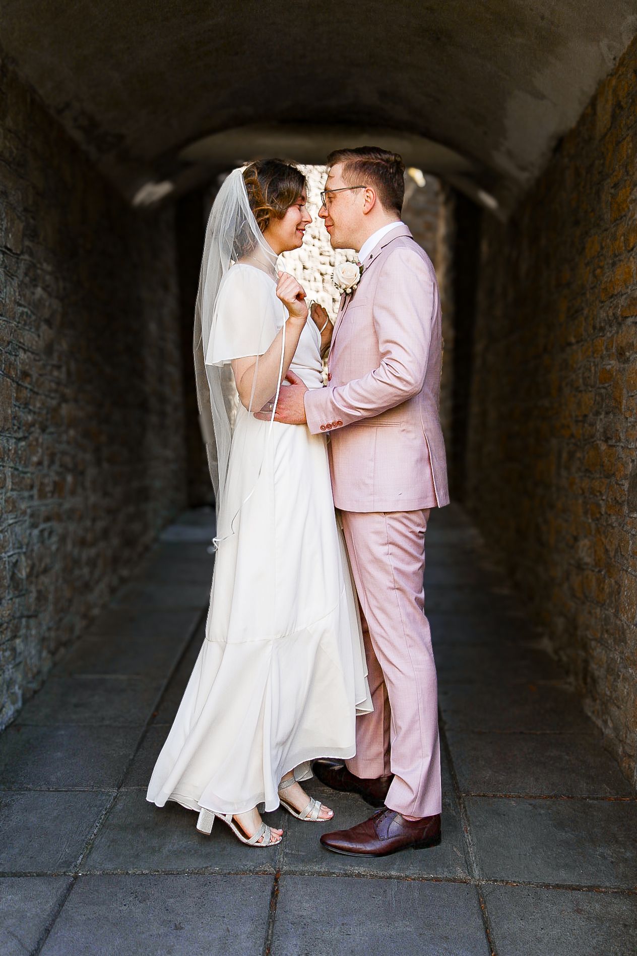 A romantic dance sequence under a stone archway with a couple in pink and white formal attire.