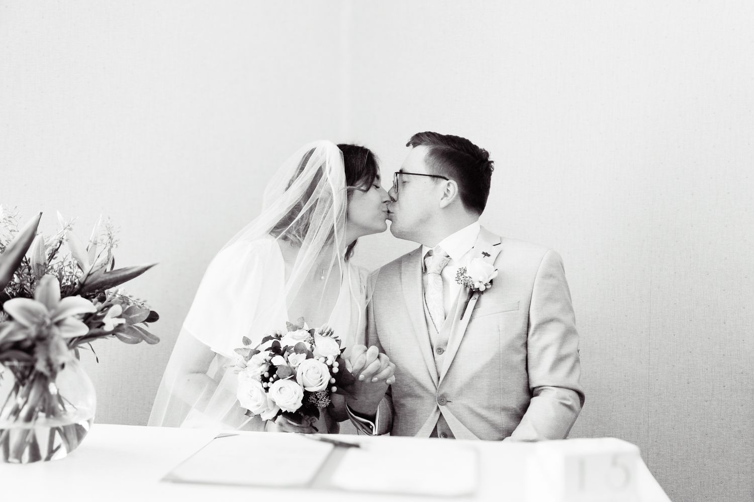 Wedding couple signing documents at a table in an elegant indoor ceremony setting.