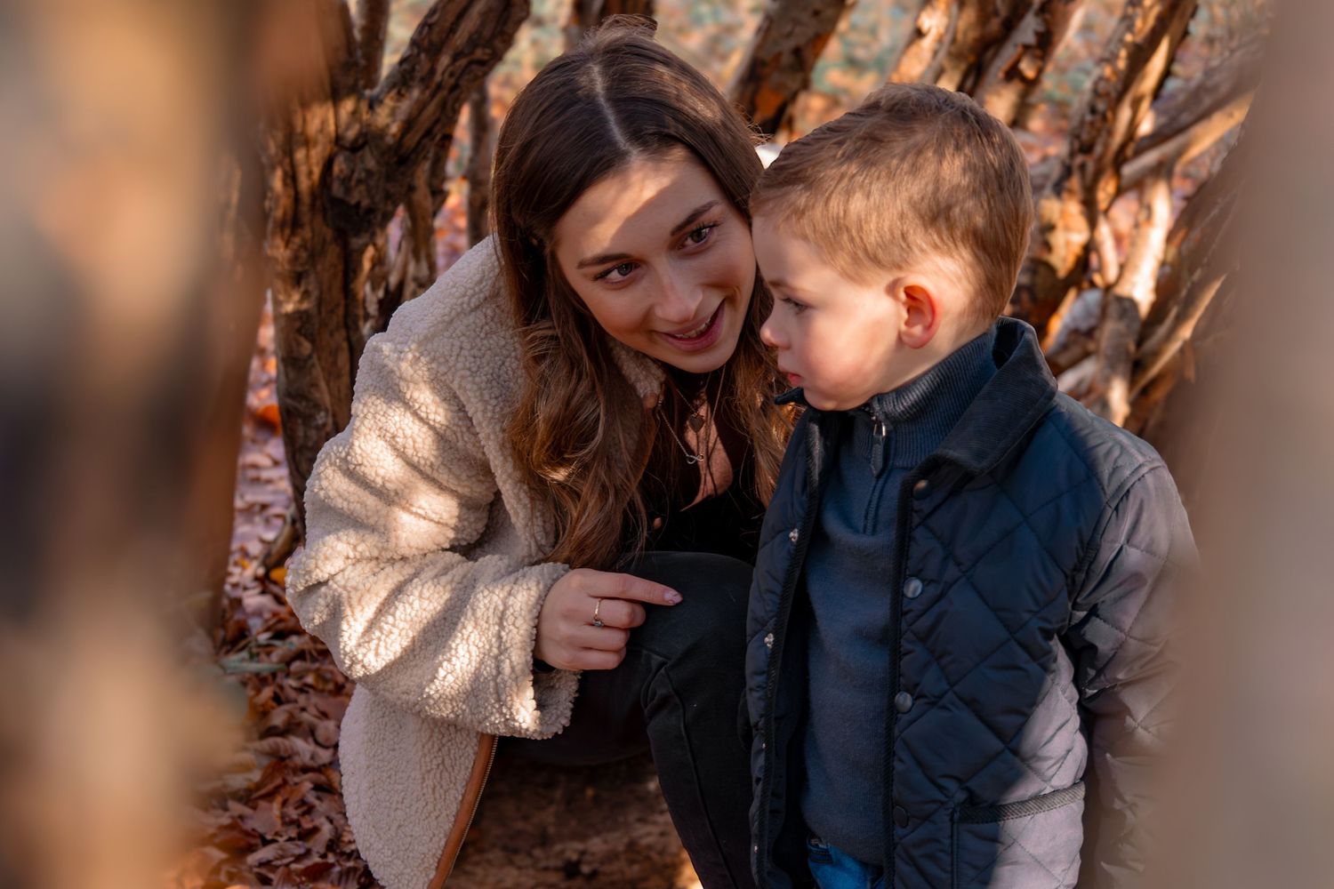 Family shares tender moments among fall foliage and tree trunks.