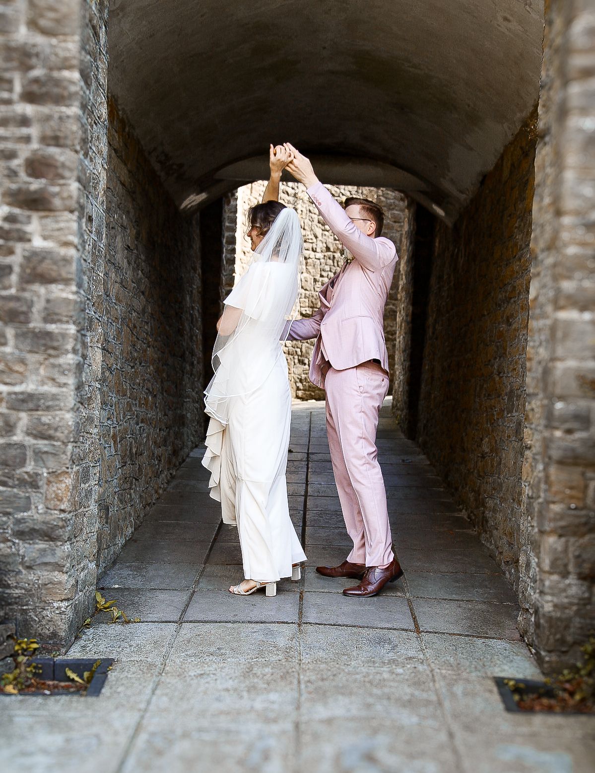 Sequence of playful dance moves captured in a historic stone archway.
