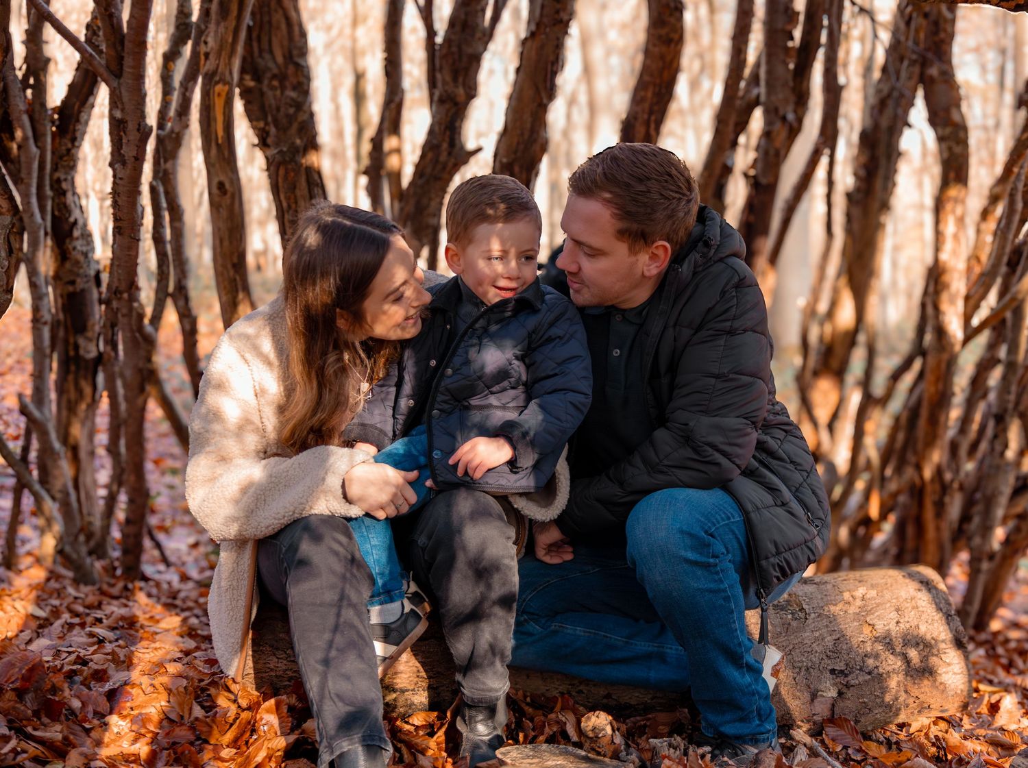 Family gathering captured in warm autumn light between forest trees.