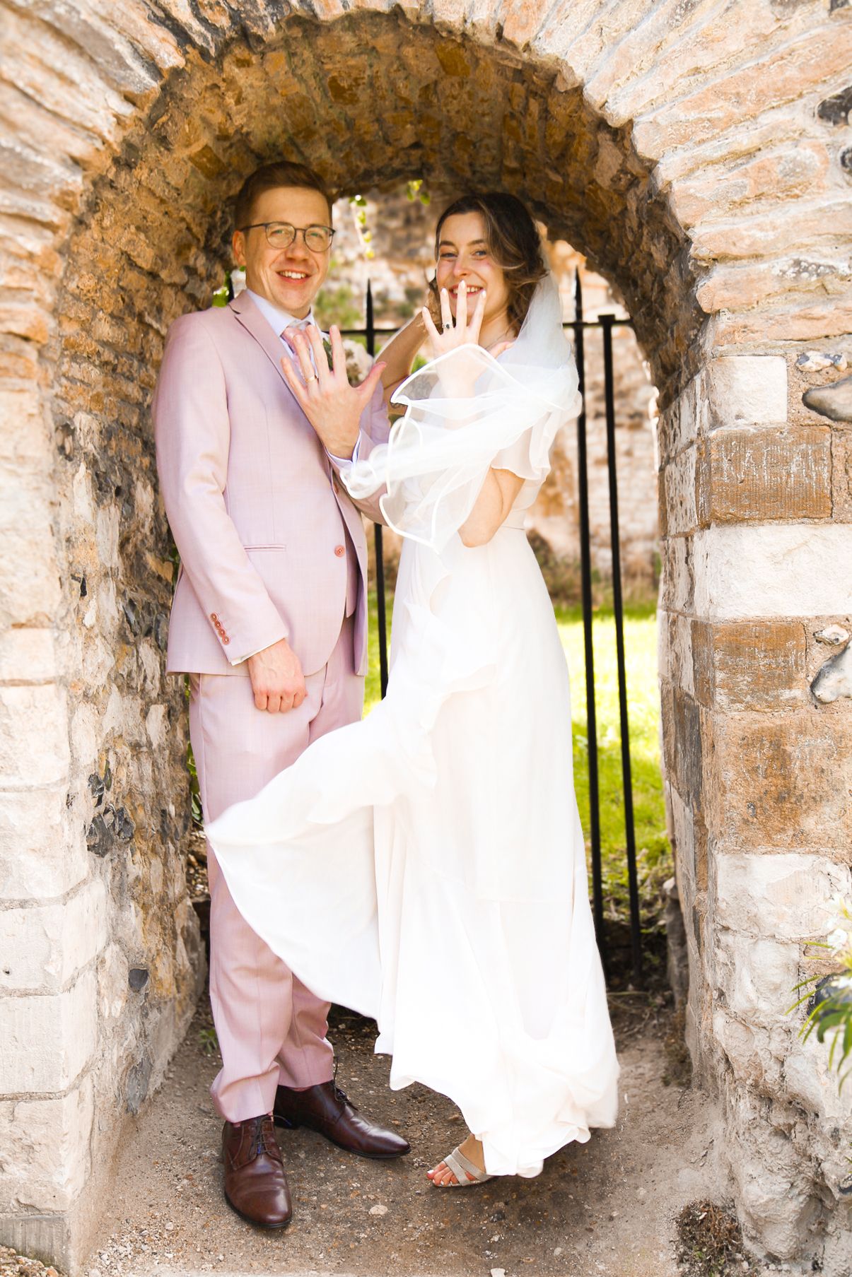 Series of romantic poses under a stone archway with natural lighting.