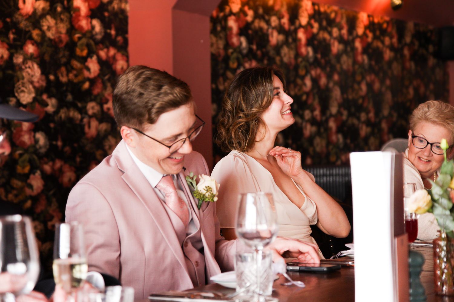 Reception scene with warm lighting and floral decorations in background.