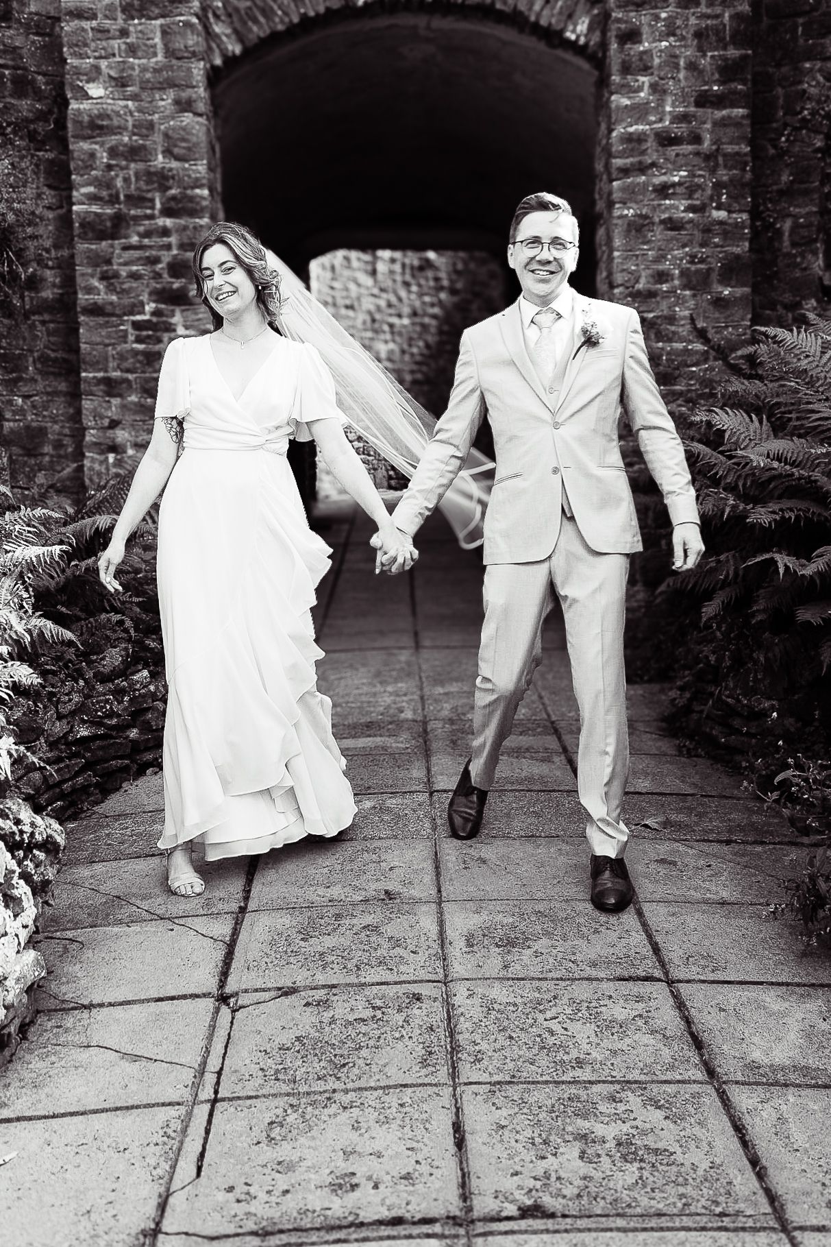 Playful wedding photos of couple dancing and jumping on stone pavement.