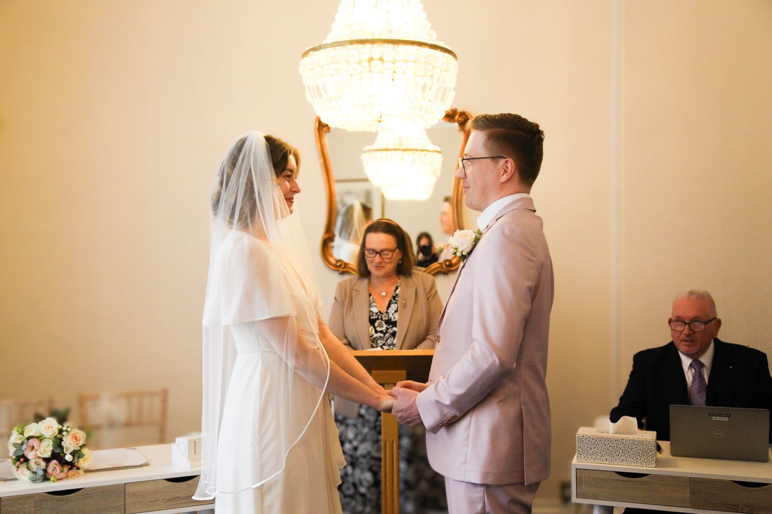 Intimate indoor wedding ceremony with warm lighting and couple signing paperwork.