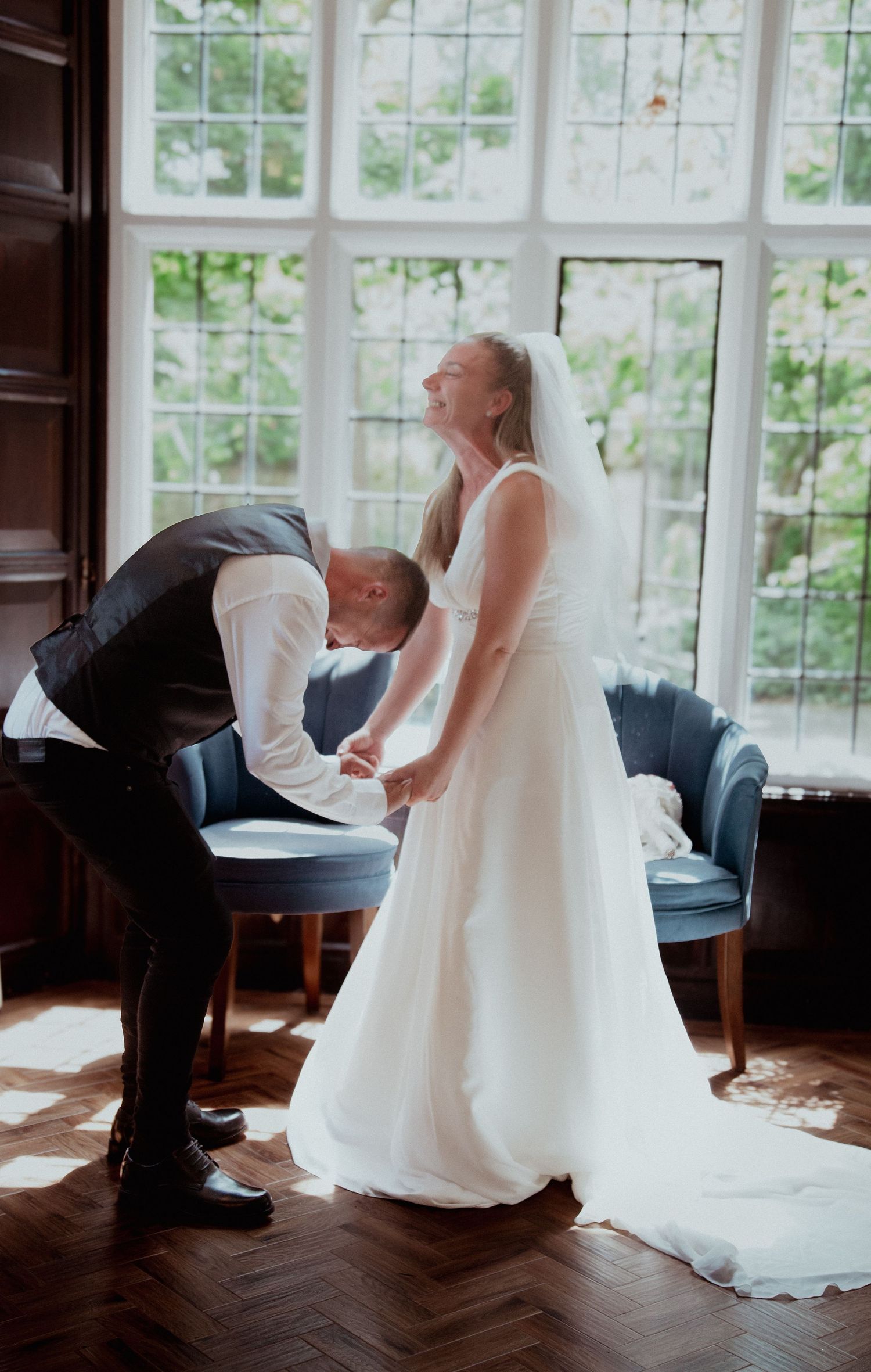 Wedding couple performing a traditional shoe game in a bright windowed room.