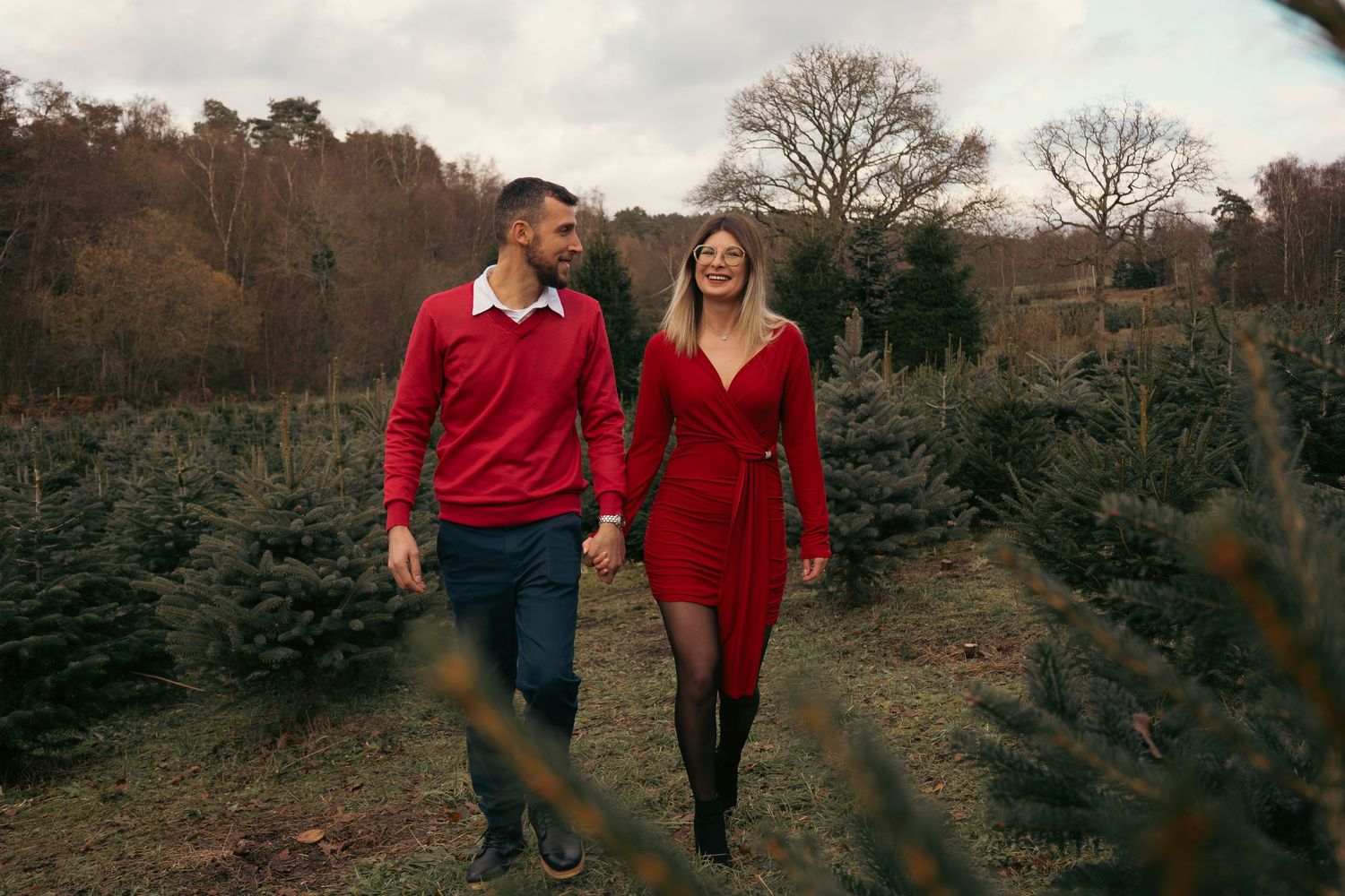 Couple walking hand in hand through autumn landscape with long shadows.