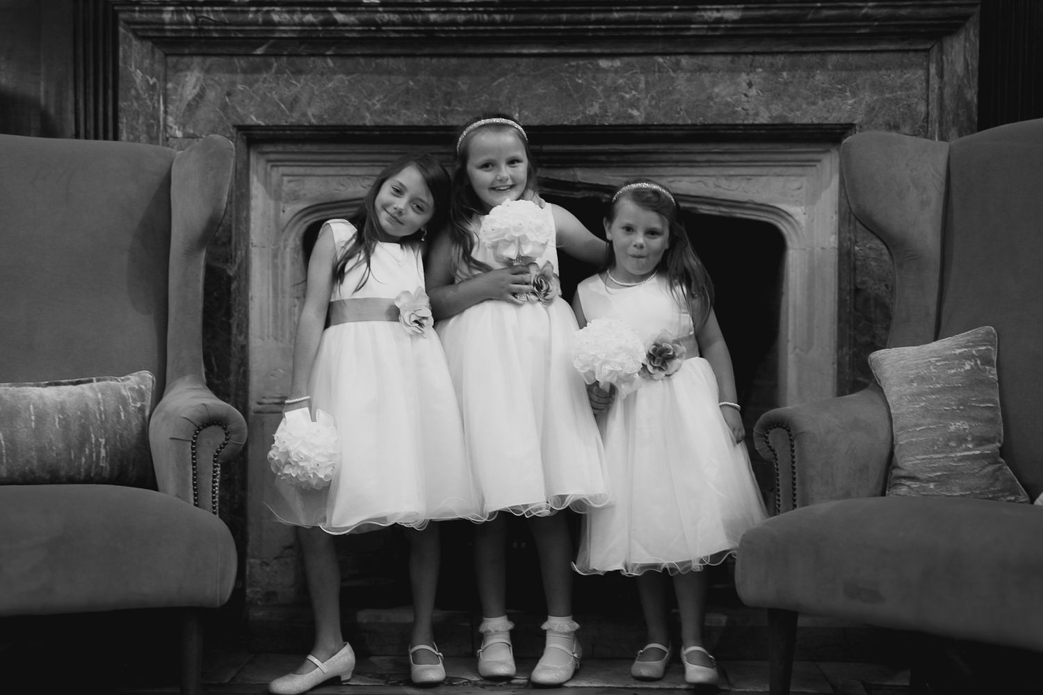 Children in formal attire sit together on a vintage couch.