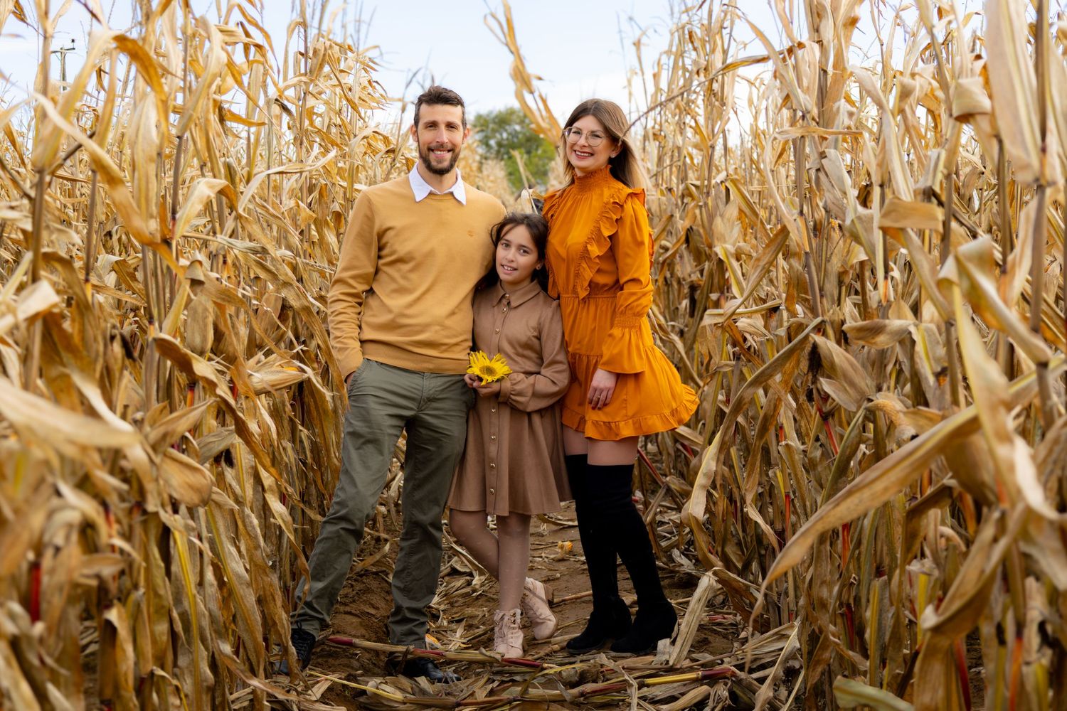 Group portrait of people exploring a tall cornfield maze during harvest season.