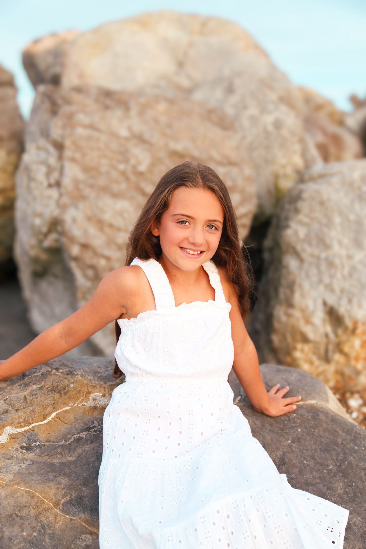 White sundress photo series on rocky beach at sunset.