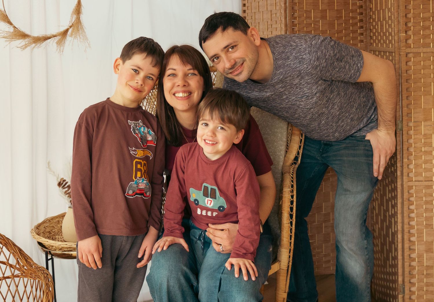 Happy family of four with two young boys poses together in cozy indoor portrait session setting.