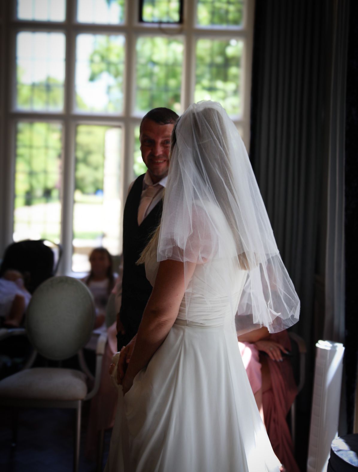 Silhouetted wedding couple against bright windows in an indoor venue.
