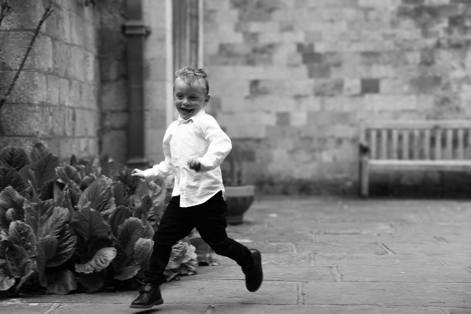 A playful sequence of a child running and jumping across a stone courtyard.