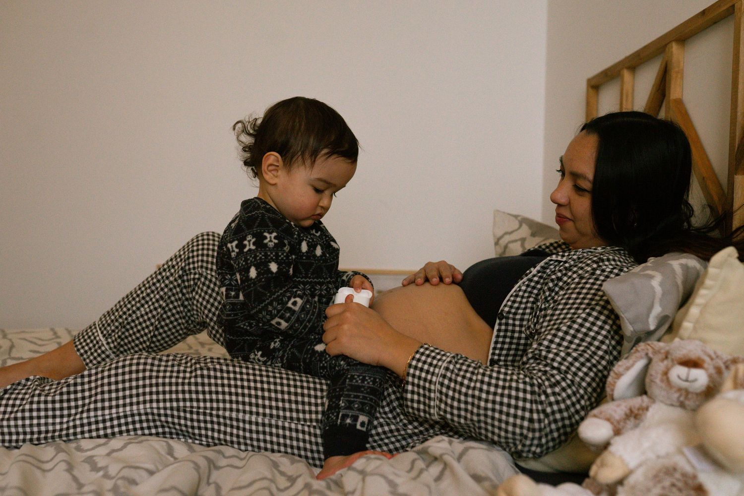seance photo grossesse et famille avec un bébé qui joue sur maman dans le lit à Marseille