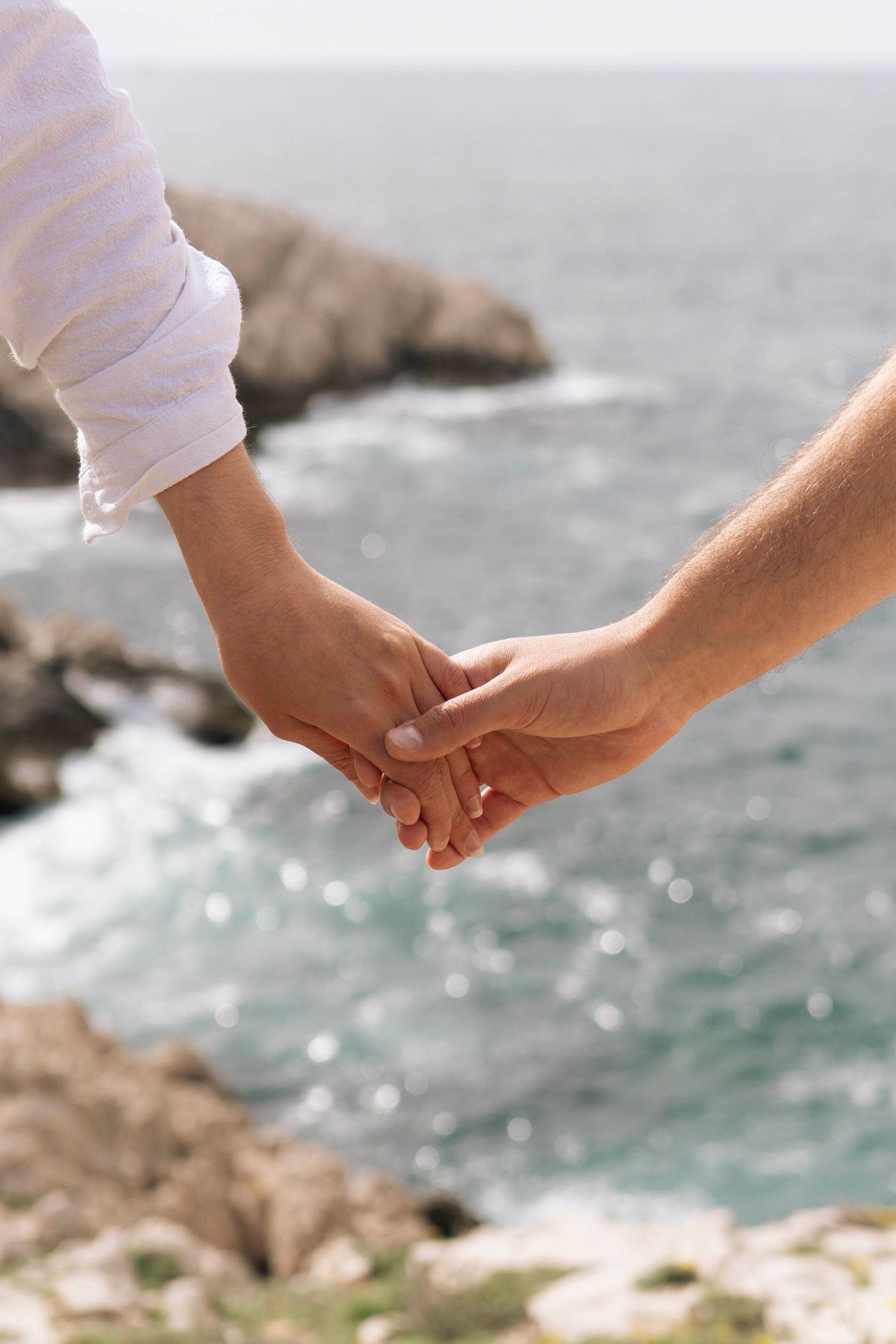 des mains d'amoureux qui se serrent lors d'une séance photo couple en bord de mer à Marseille