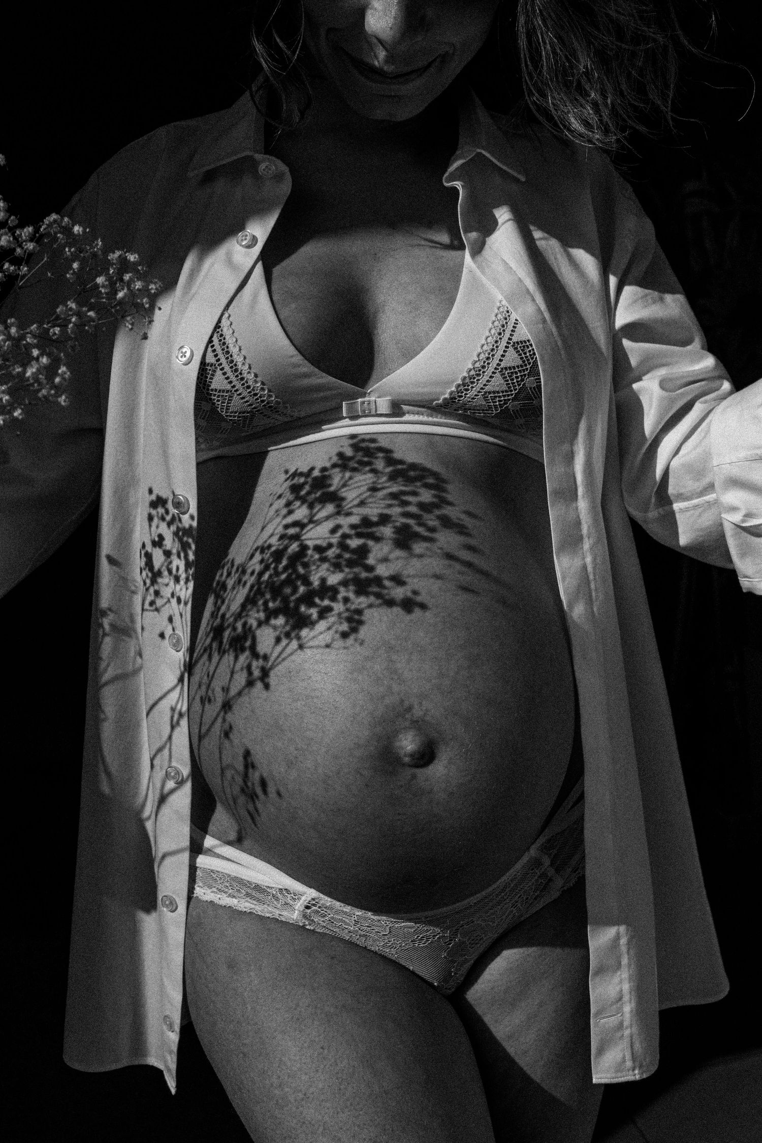 seance photo grossesse à domicile à marseille focus détail ventre en noir et blanc et fleurs séchées