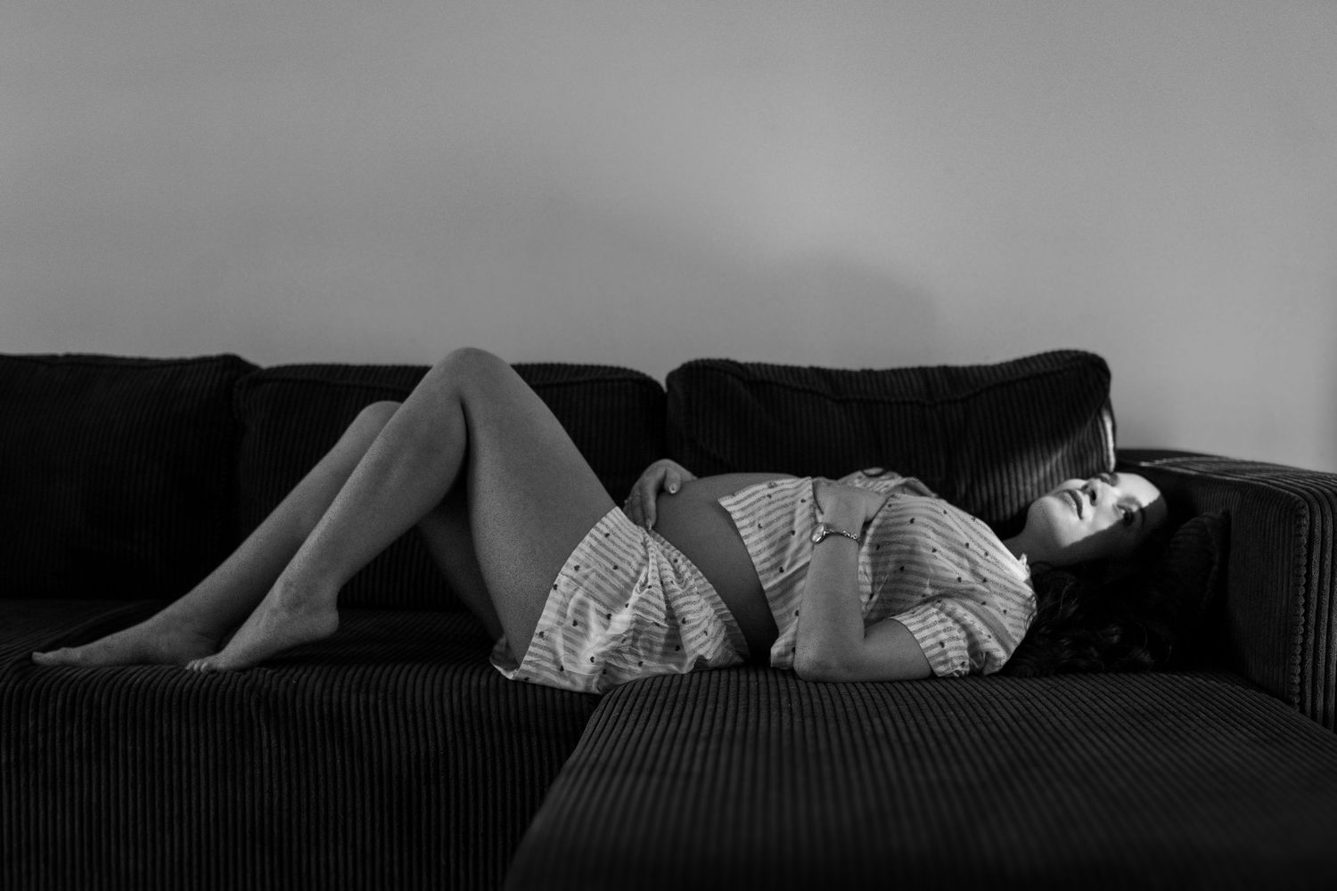 seance photo grossesse à domicile à marseille avec la maman allongée sur son canapé en noir et blanc